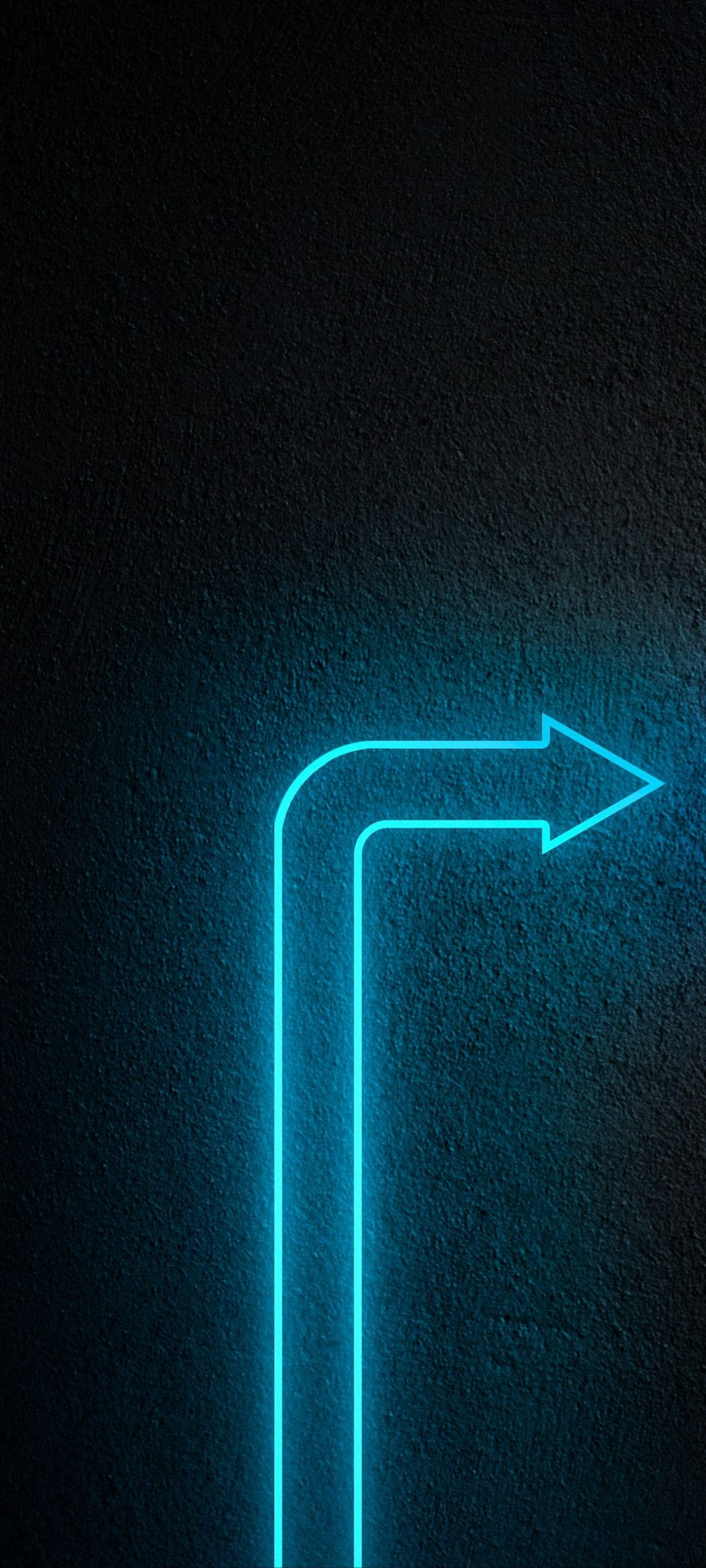 Cyan neon arrow glowing on a black textured wall with a sharp curve pointing right in a minimalist dark room.