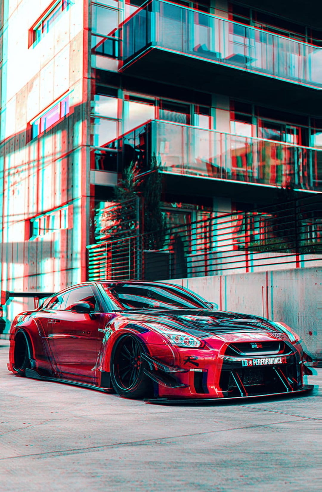 Red Nissan GT-R with a widebody kit parked near a modern building features a 3D red-cyan anaglyph effect.
