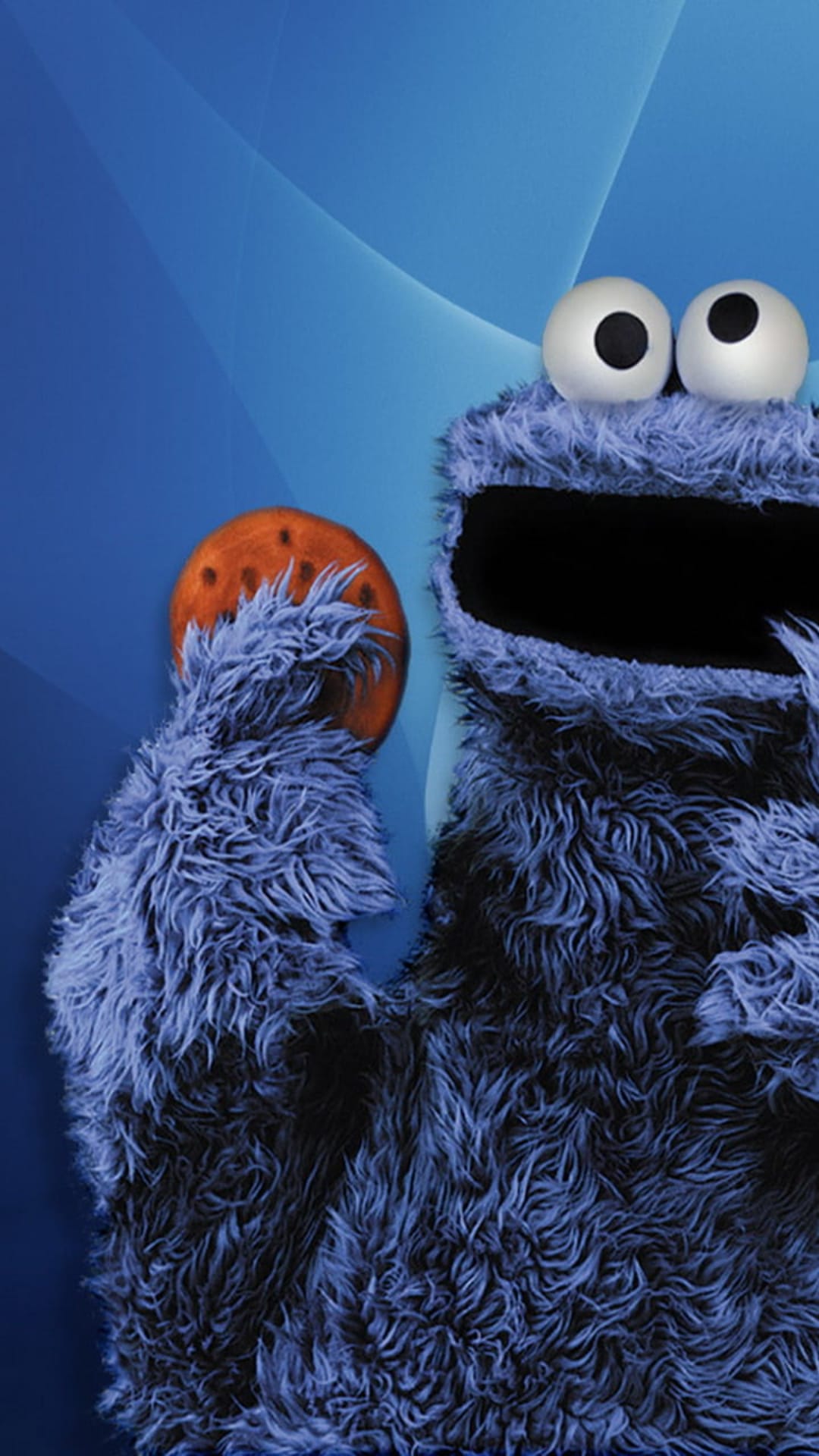 Cookie Monster clutches a chocolate chip cookie with his furry blue hand against a soft blue textured backdrop.