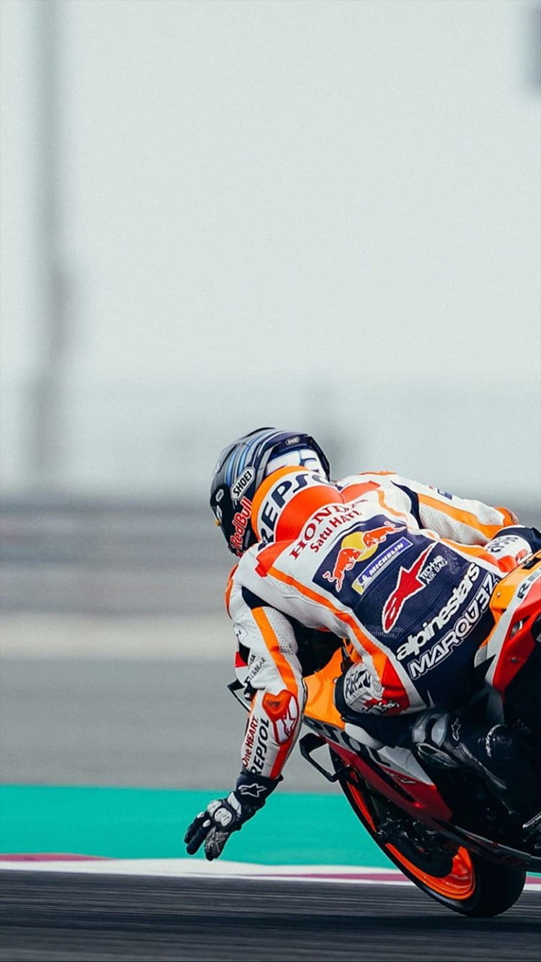 Marc Marquez leans low on a Repsol Honda motorcycle while racing through a corner at high speed on a track.