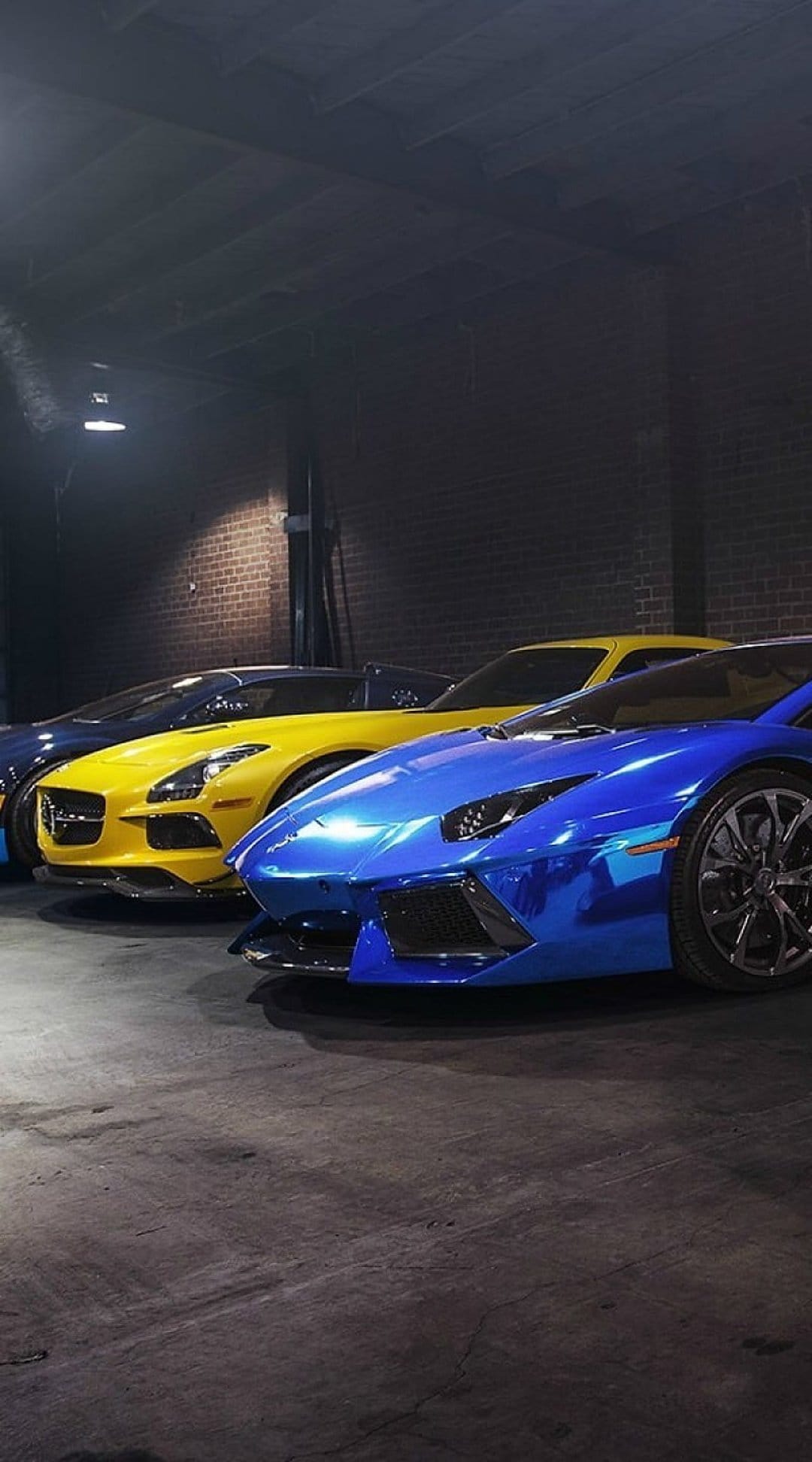 Blue Lamborghini and yellow Mercedes SLS AMG in a dark garage with shadows and polished metallic reflections.