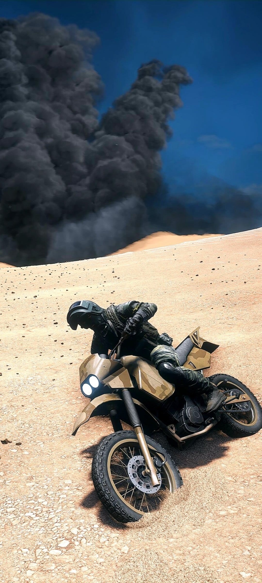 Soldier in full gear riding a dirt bike across sand as a towering black smoke cloud rises into a clear blue sky.