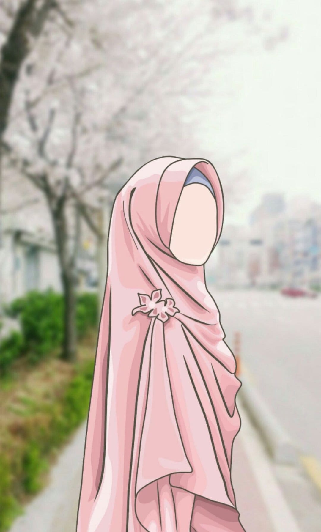 Young woman in a pink hijab and floral brooch stands before a blurred street with trees and buildings in daylight.
