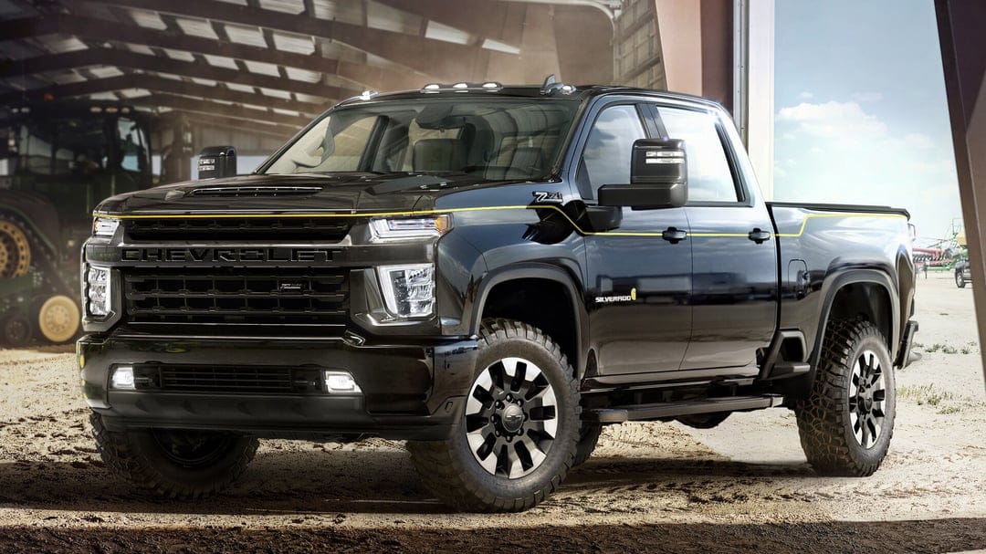 Black Chevrolet Silverado Z71 pickup truck with gold accents parked in a rustic barn with off-road tires.