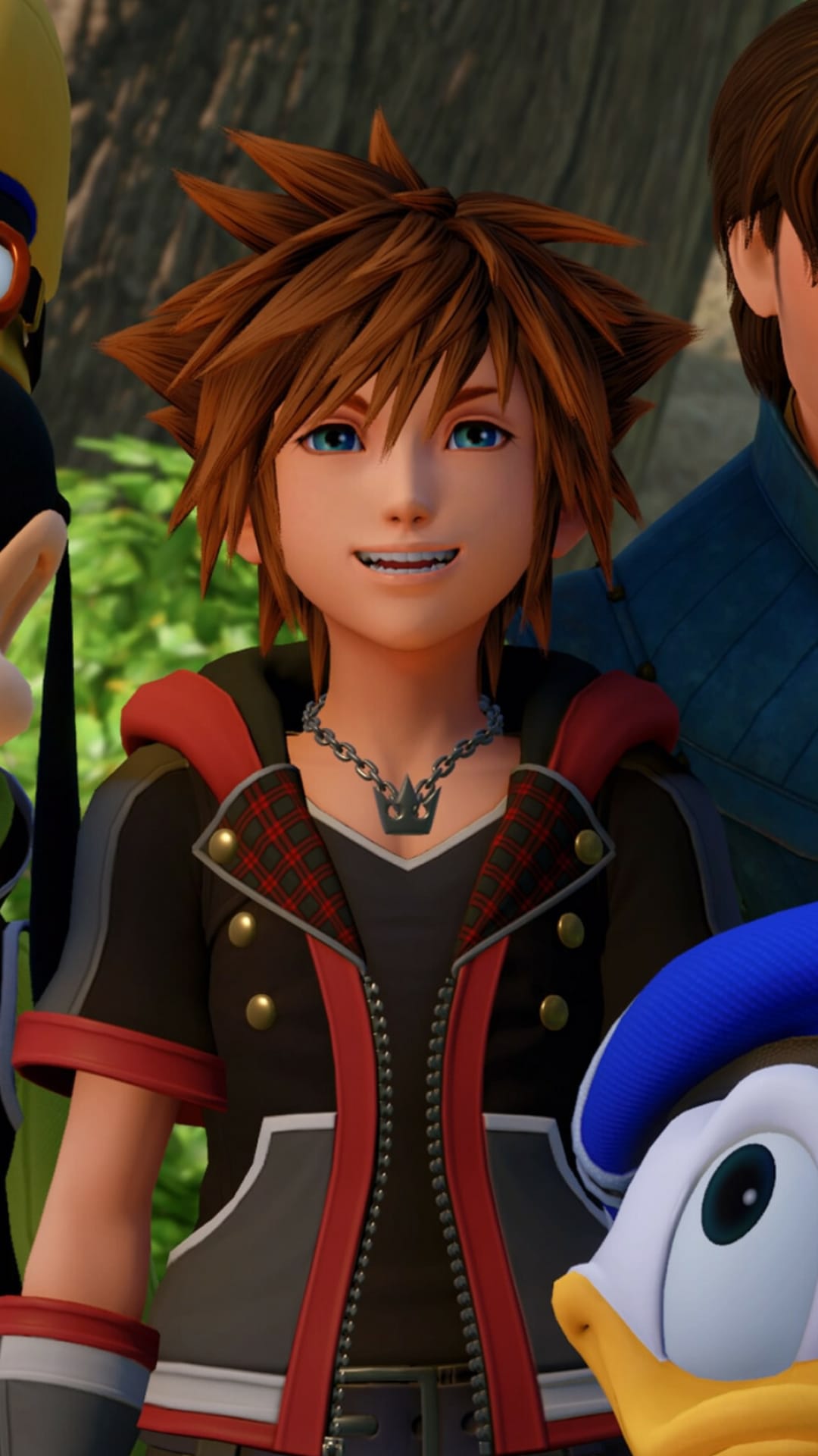 Sora with spiky brown hair smiles in a black and red vest with a crown necklace against a lush green forest background.