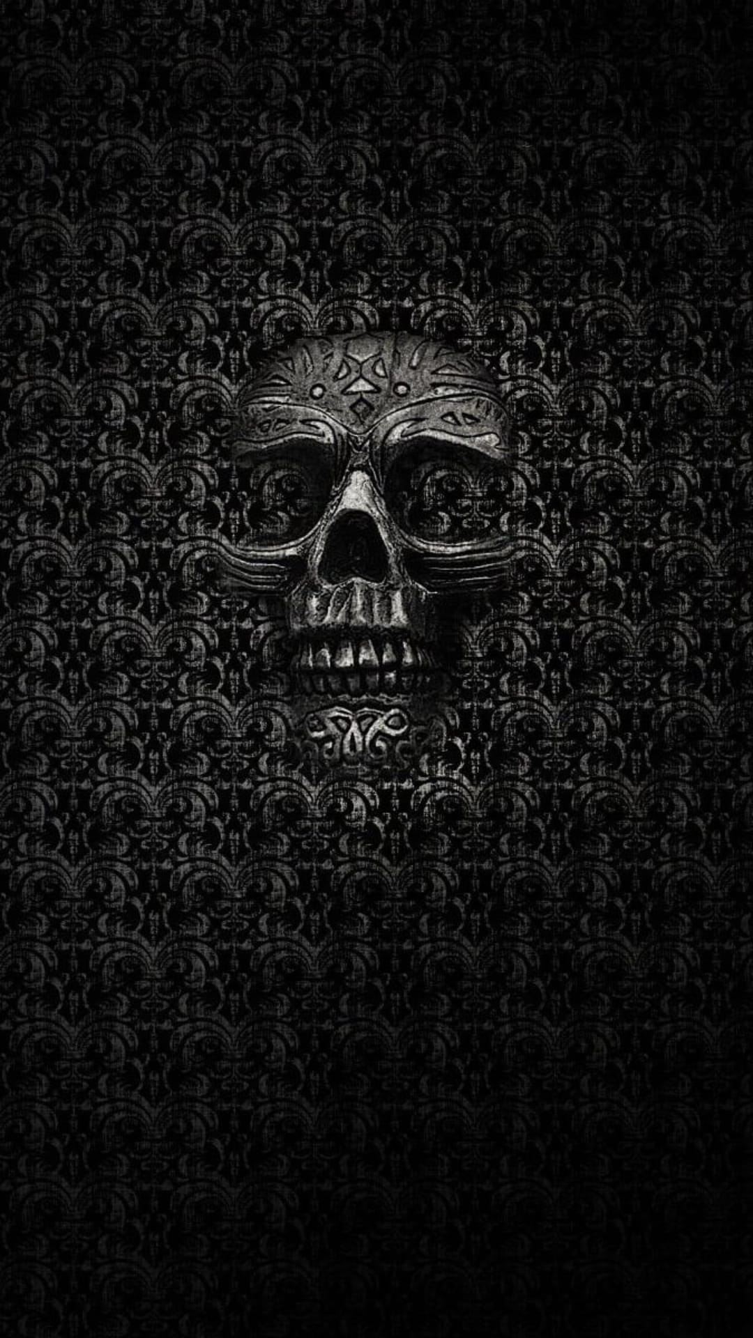 Metallic skull with star carvings positioned against a black textured damask wallpaper with floral motifs.