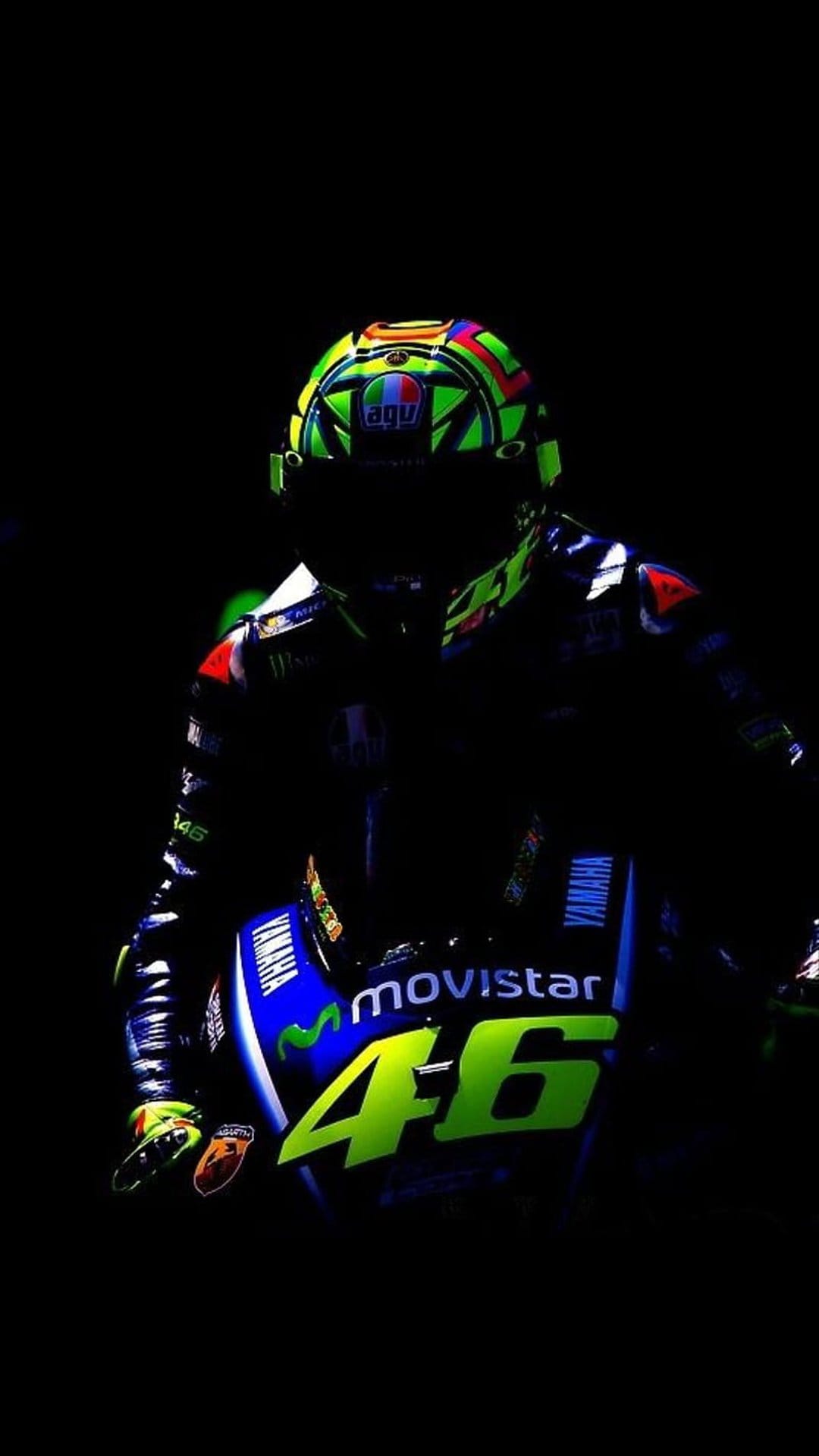Valentino Rossi in full racing leathers crouches behind the Movistar Yamaha windscreen on a professional track.