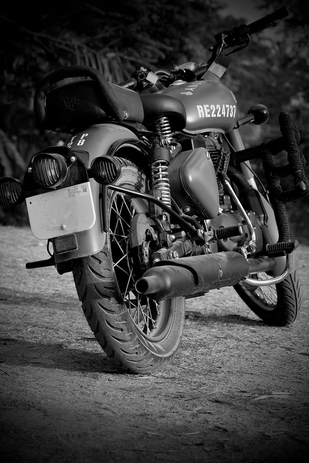 Royal Enfield motorcycle rear tire and exhaust pipe in a black and white close-up with a soft blurred background.