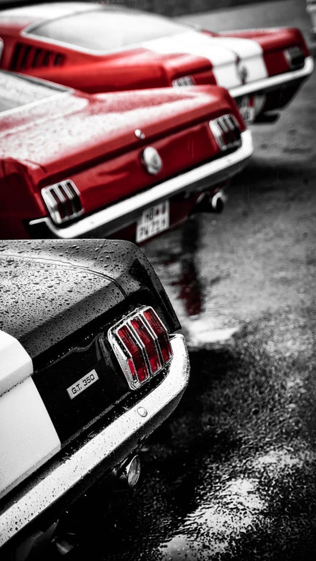 Red Ford Mustang GT 350 rear with glowing taillights parked on a dark wet street during a rainy night.