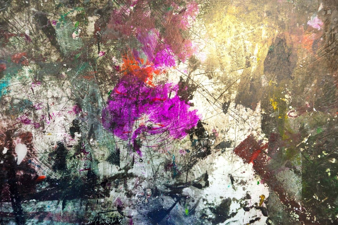 Purple and pink paint splatters mix with green smears on a heavily textured, glossy white and grey surface.