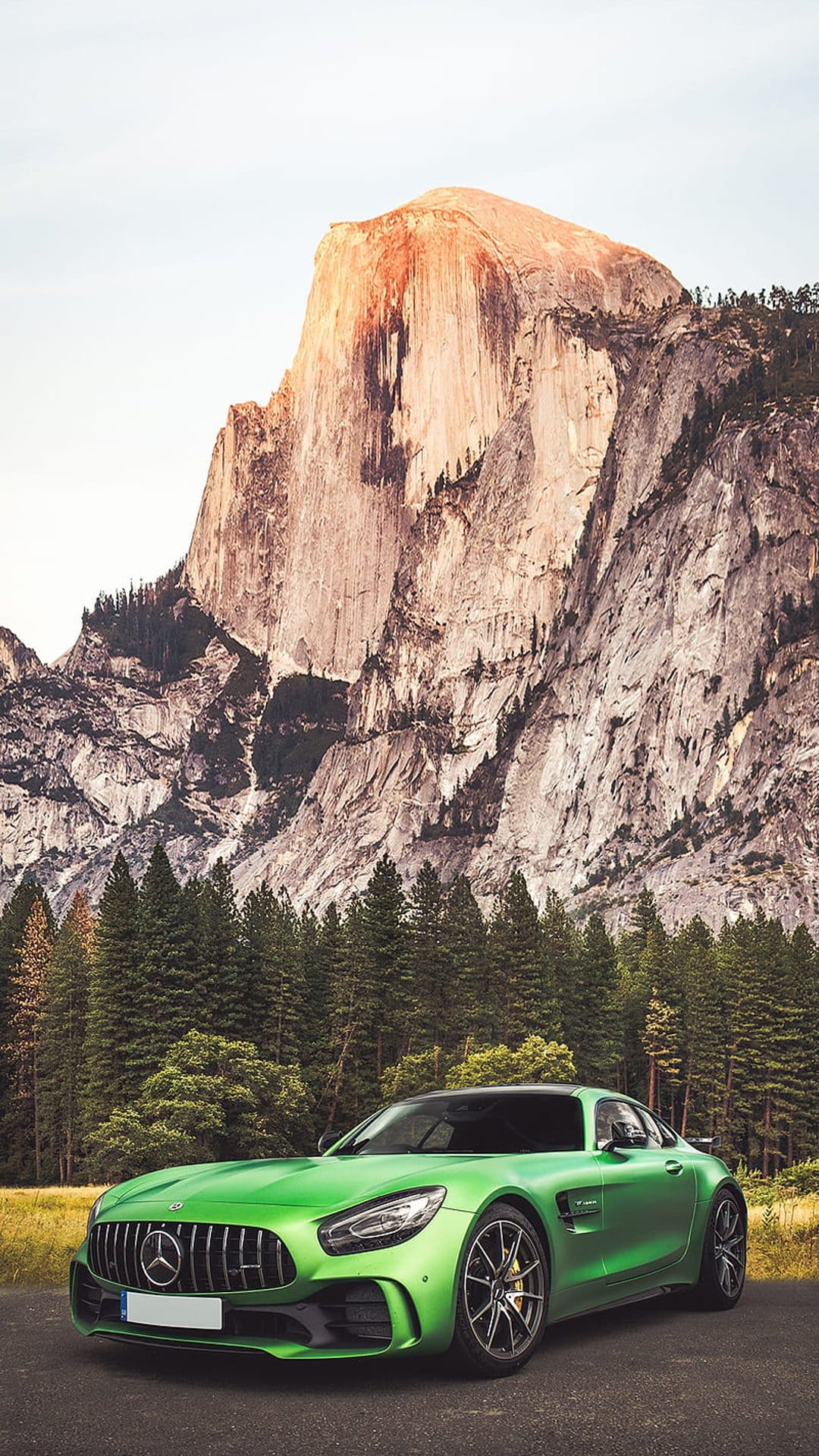 Green Mercedes AMG GT parked on a Yosemite road with Half Dome and pine forests under golden hour light.