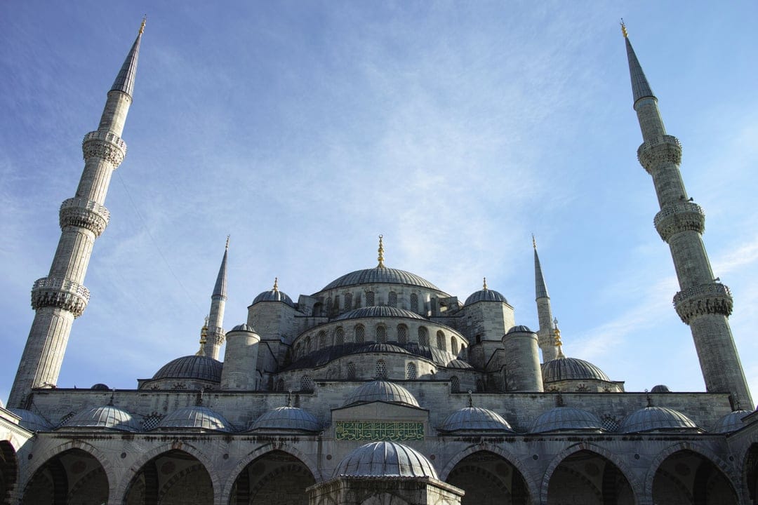 Sultan Ahmed Mosque minarets and grey domes against a clear blue sky, showing intricate Ottoman architecture.