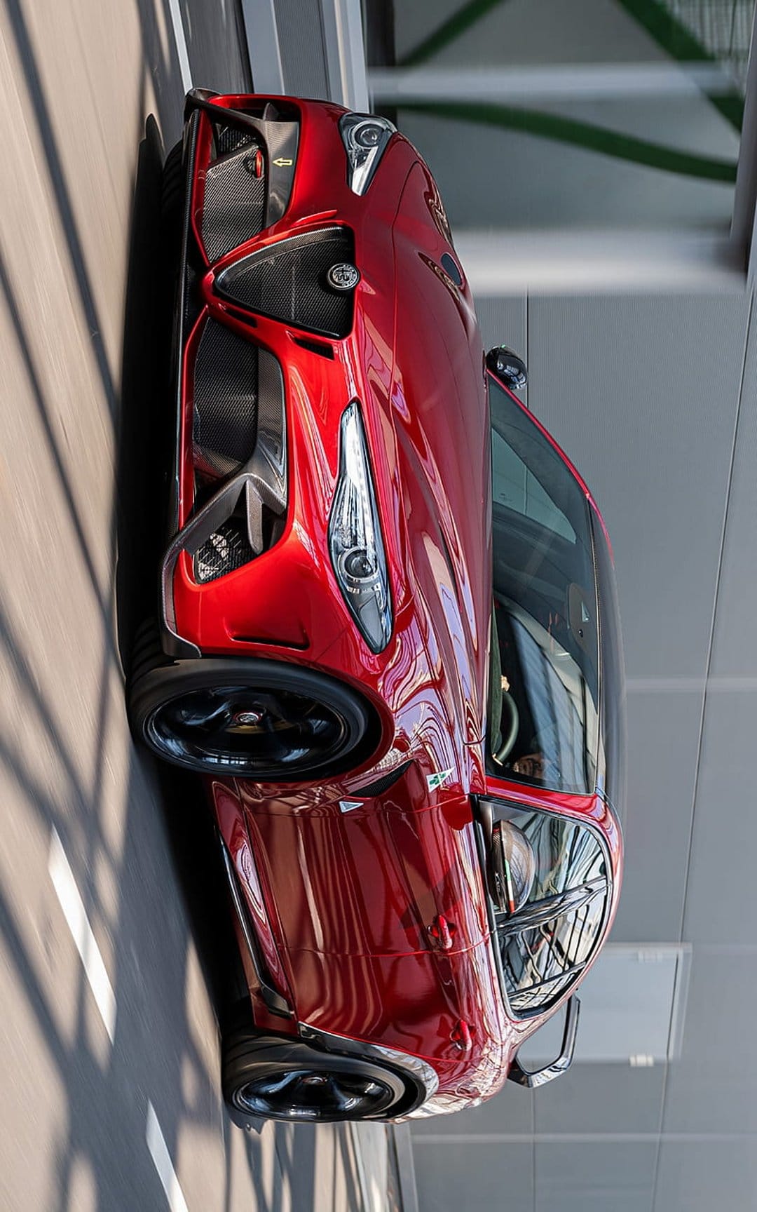 Red Alfa Romeo sports car features sharp LED headlights and glossy paint from a low-angle front perspective.