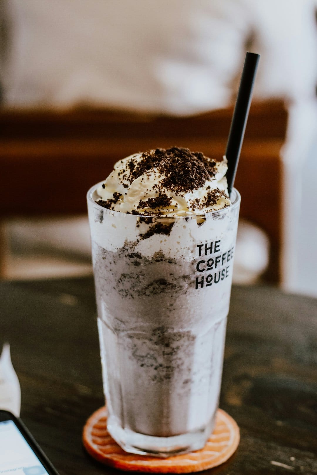 Oreo milkshake with whipped cream and cookie crumbles in a glass featuring The Coffee House logo on the front.