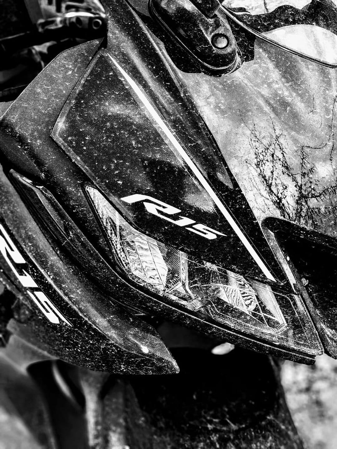 Yamaha R15 motorcycle headlight and dusty front fairing shown in a sharp black and white close-up photograph.