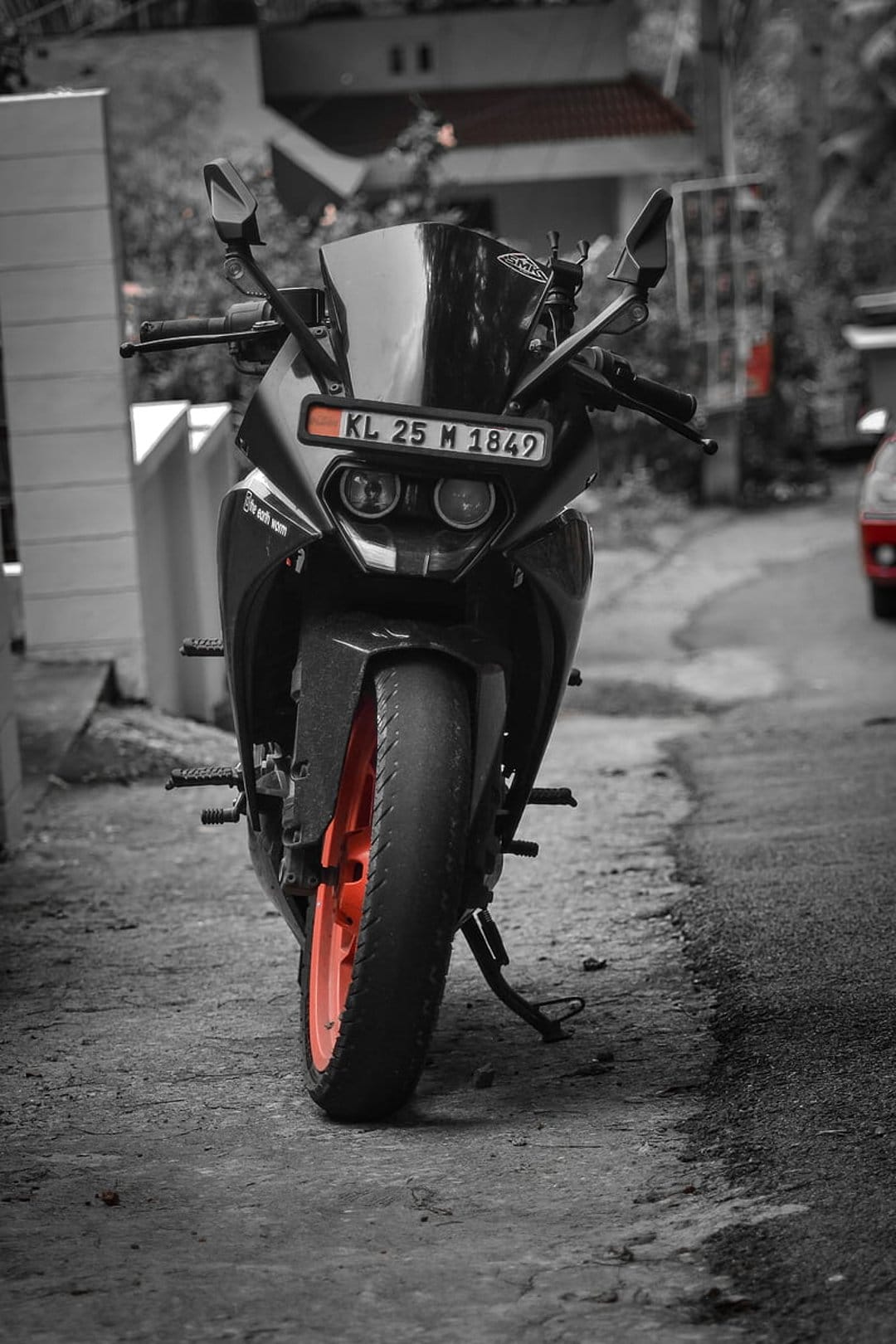 KTM motorcycle with a bright orange front wheel and black chassis parked on a paved street at a close-up angle.