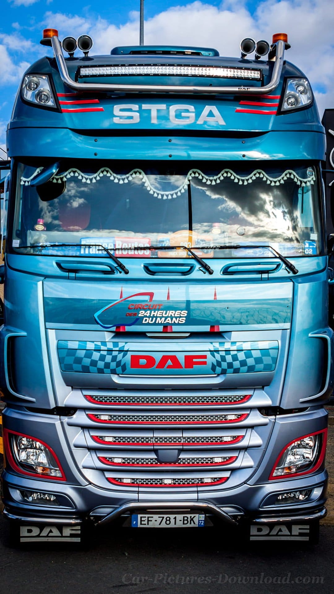 Blue DAF truck front view with Le Mans racing decals, red headlight accents, and a polished chrome bumper.