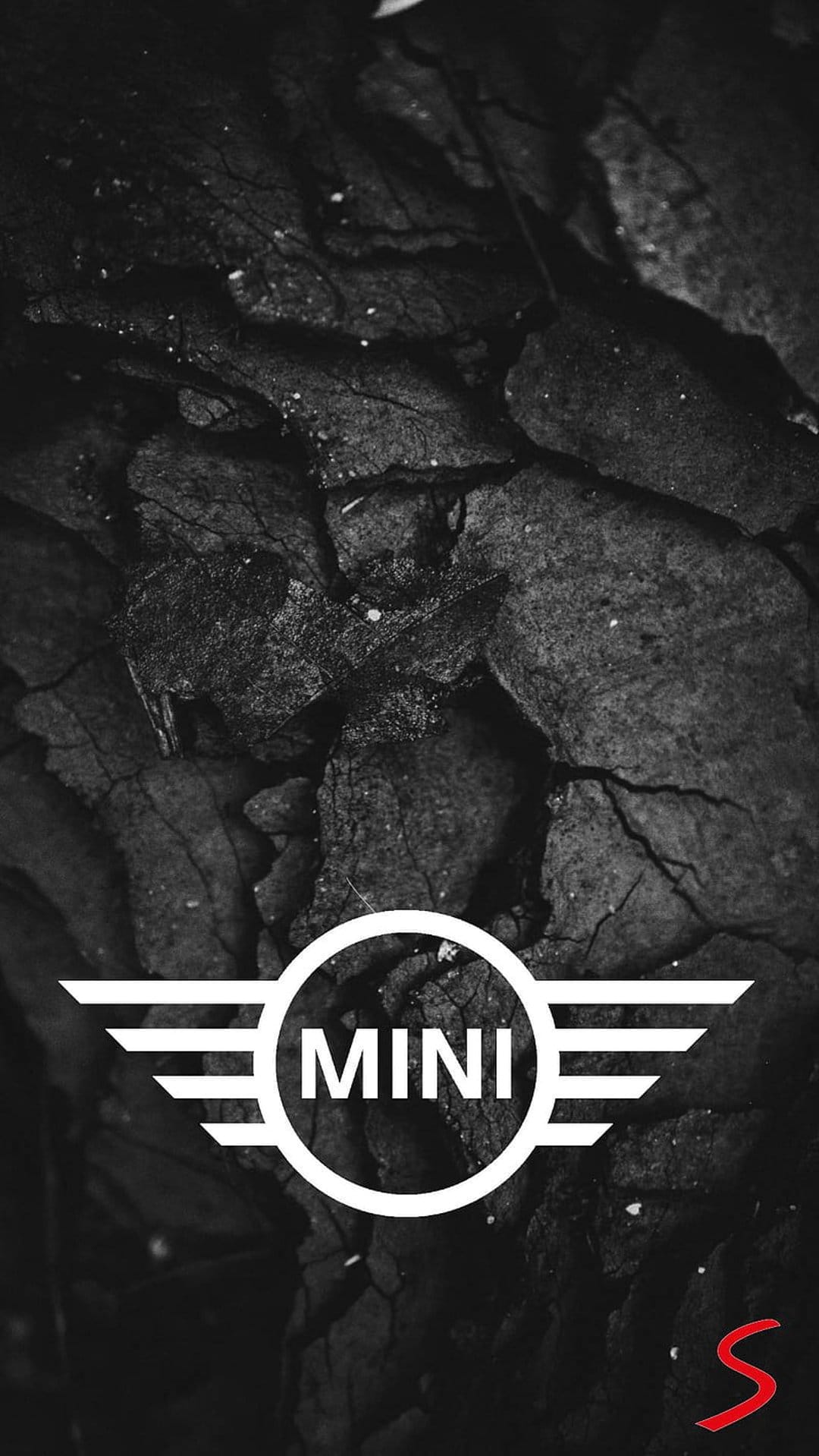 MINI logo with wings on a dark cracked charcoal background featuring a small red S performance emblem.
