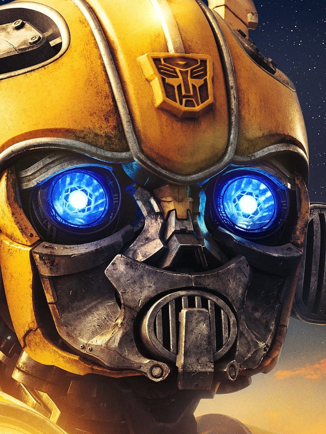 Bumblebee with glowing blue eyes and a yellow helmet stands before a sunset sky and starry night background.