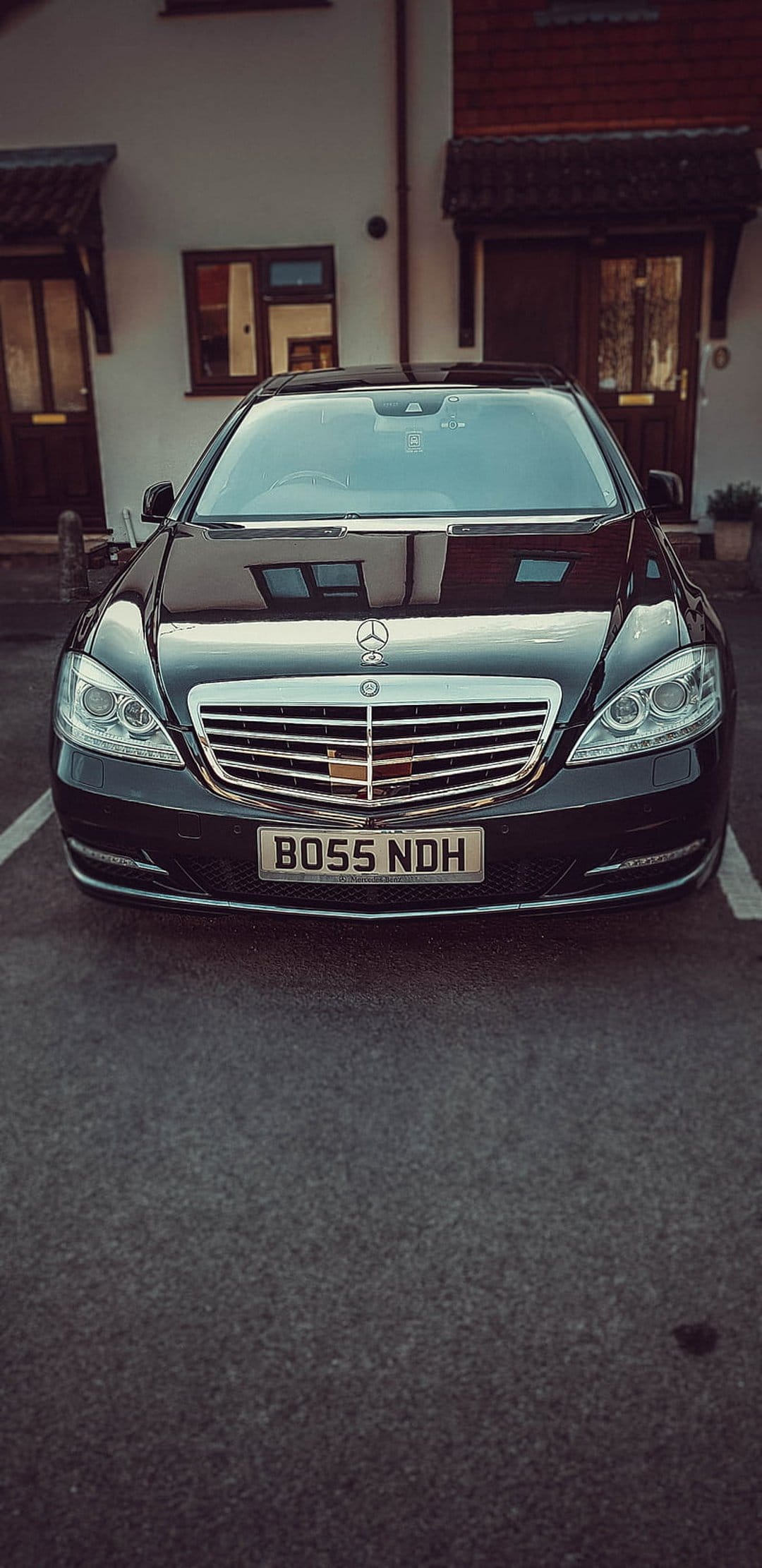 Mercedes-Benz S-Class in black featuring BOSS NDH plates and a chrome grille parked on a residential driveway.