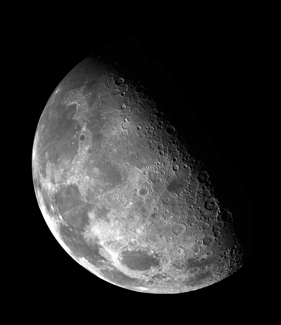 Lunar craters and rugged mountain peaks cast long shadows across the illuminated crescent of the moon's surface.