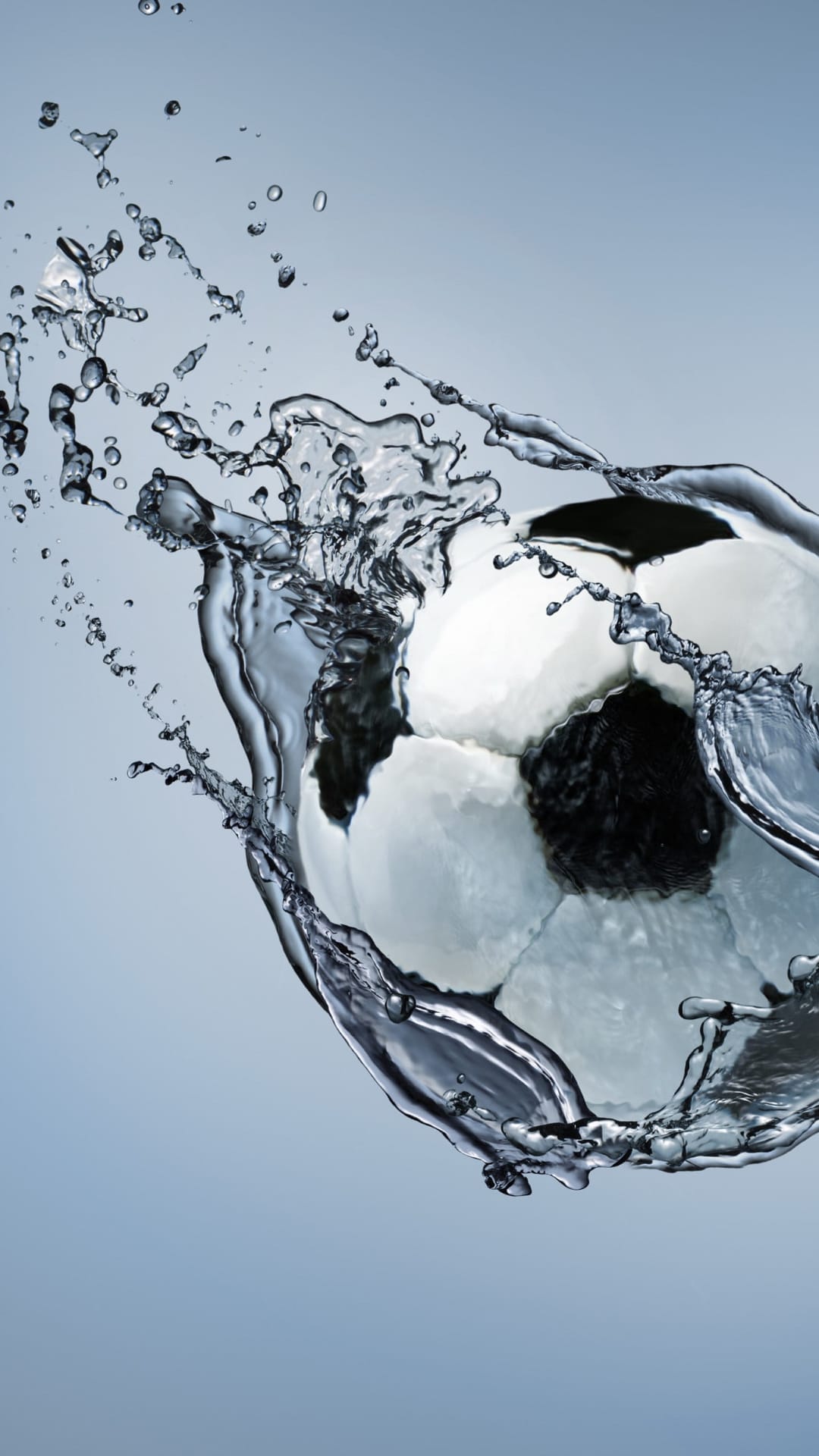 Soccer ball splashing through crystalline water with exploding droplets and ripples against a dark background.