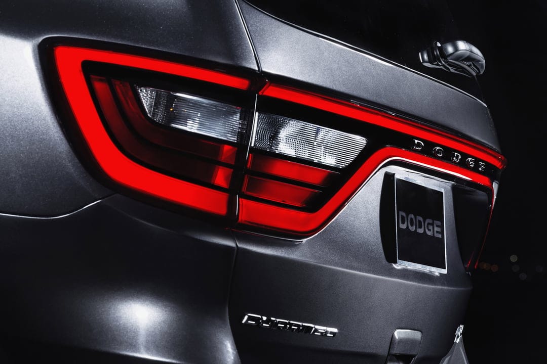 Illuminated red LED racetrack taillight on a metallic grey Dodge Durango SUV in high-contrast lighting.