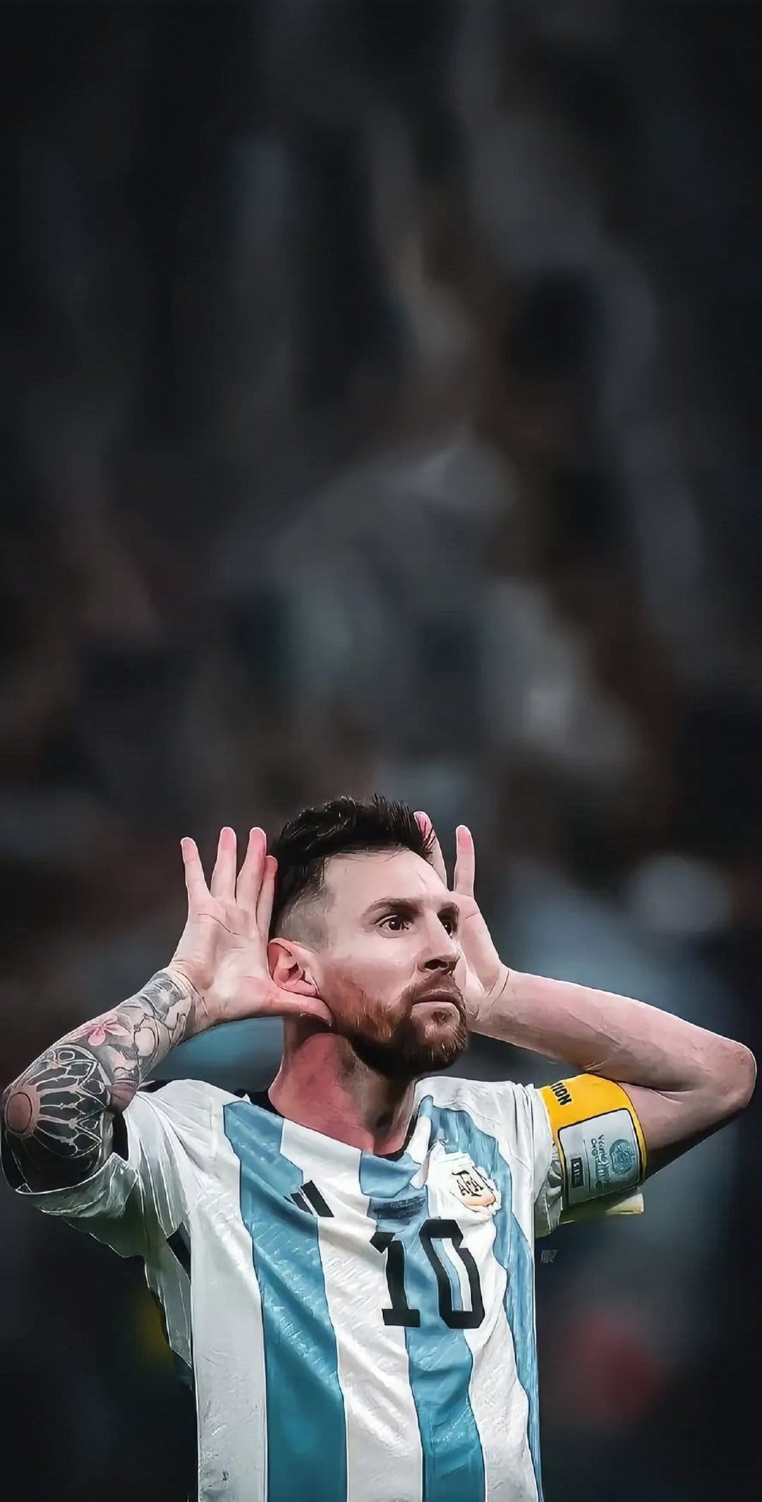 Lionel Messi in a blue and white Argentina jersey celebrates a goal with hands raised on a blurred pitch.
