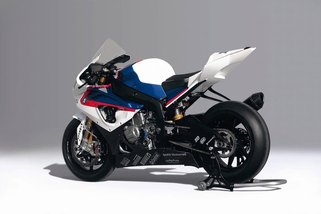 BMW S1000RR racing motorcycle in white blue and red on a rear stand against a grey studio background.