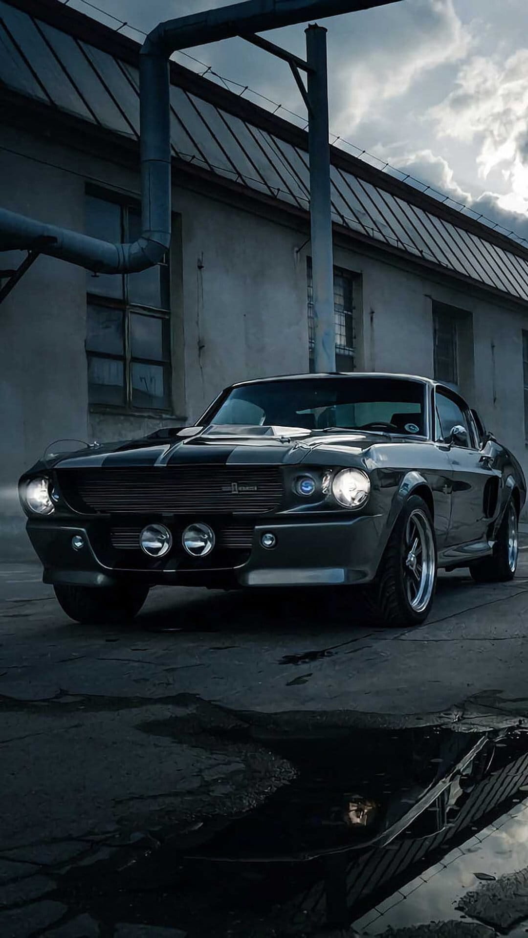 Eleanor Mustang GT500 fastback parked near a gritty brick building with low-key lighting and wet reflections.