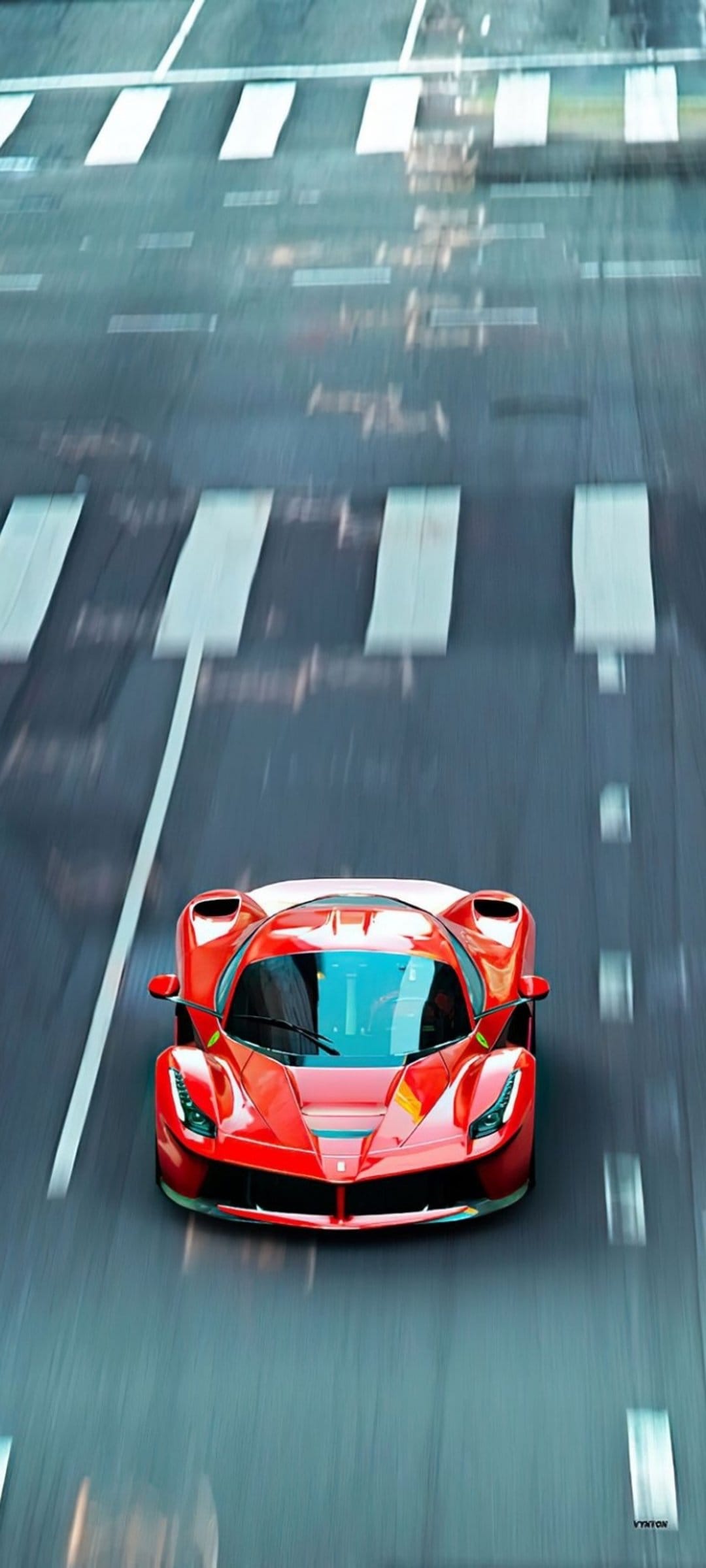 Red Ferrari supercar speeds over white pedestrian crossing markings on a reflective, wet city road.
