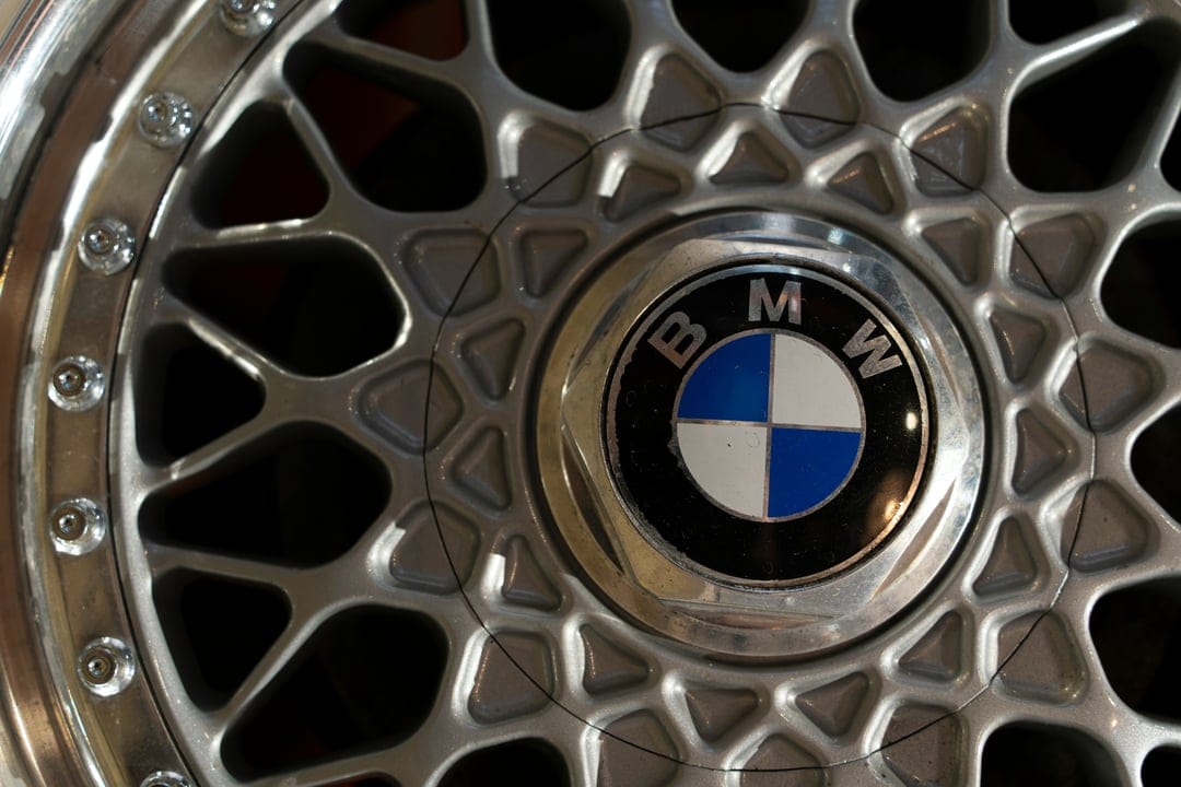 BMW circular emblem centered on a silver alloy wheel with metallic spokes and intricate macro texture details.