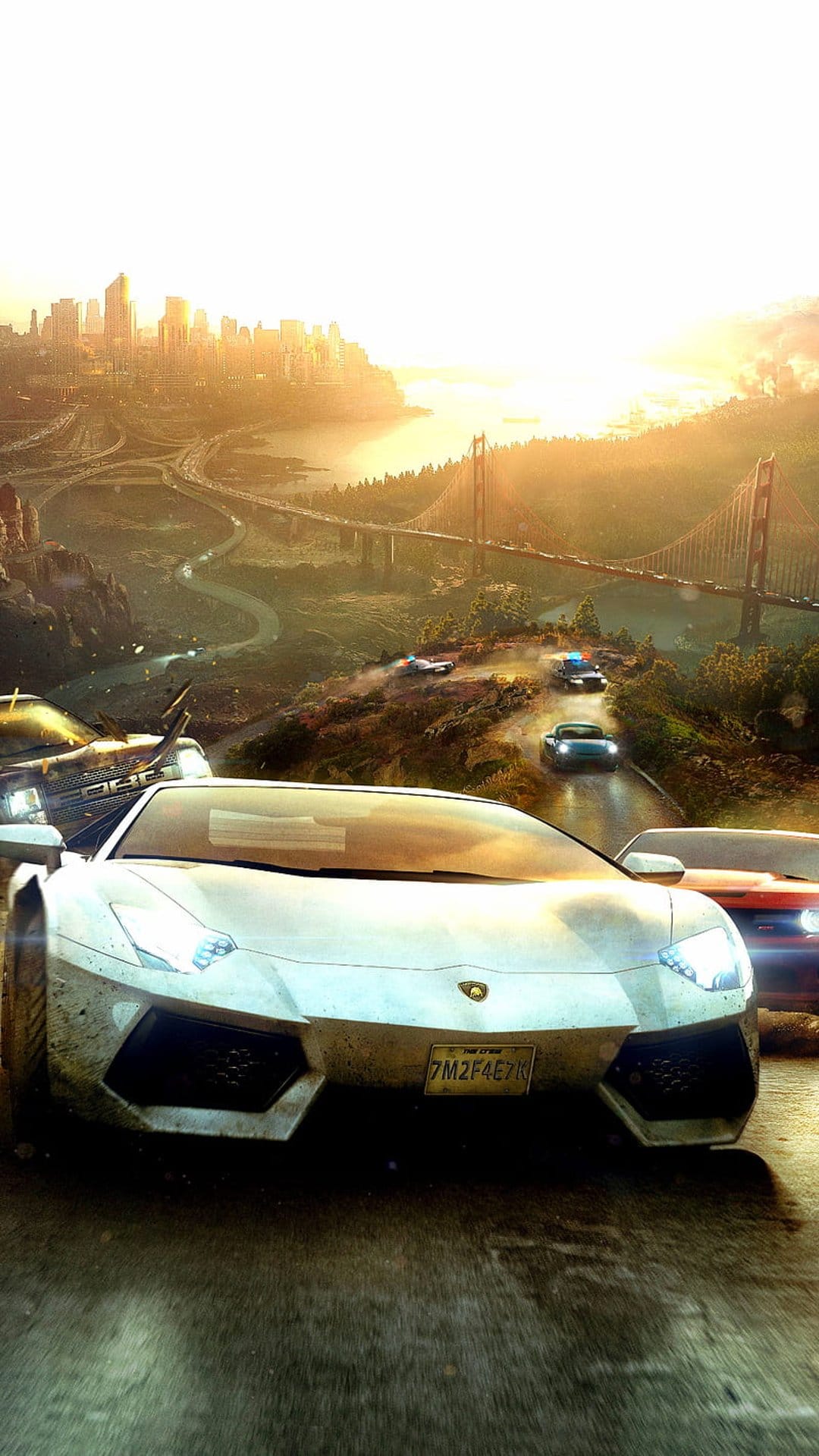 Sleek sports cars racing on a winding highway toward the Golden Gate Bridge and city skyline under a sunset sky.