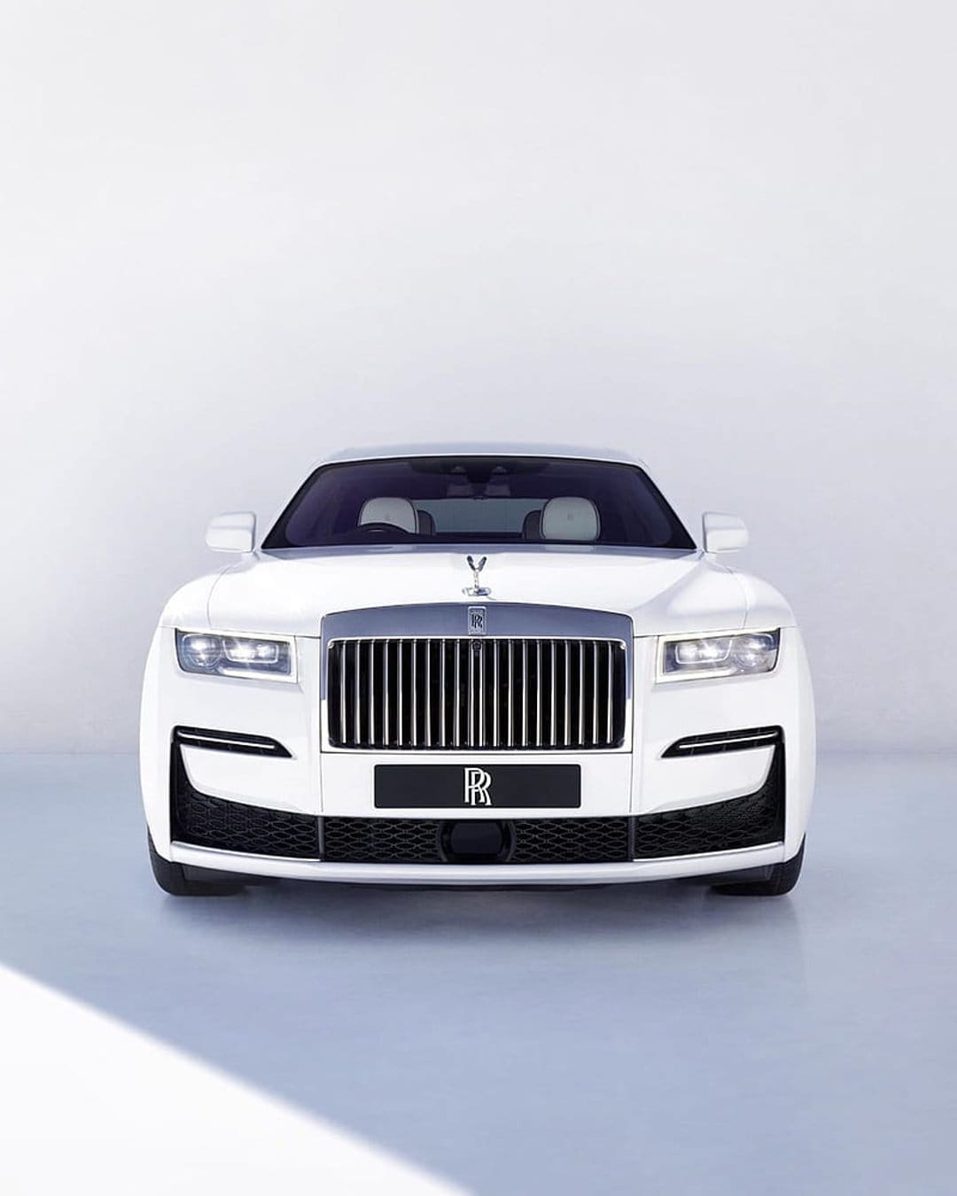 Rolls-Royce Ghost white luxury sedan showcasing a polished chrome grille and Spirit of Ecstasy hood ornament.