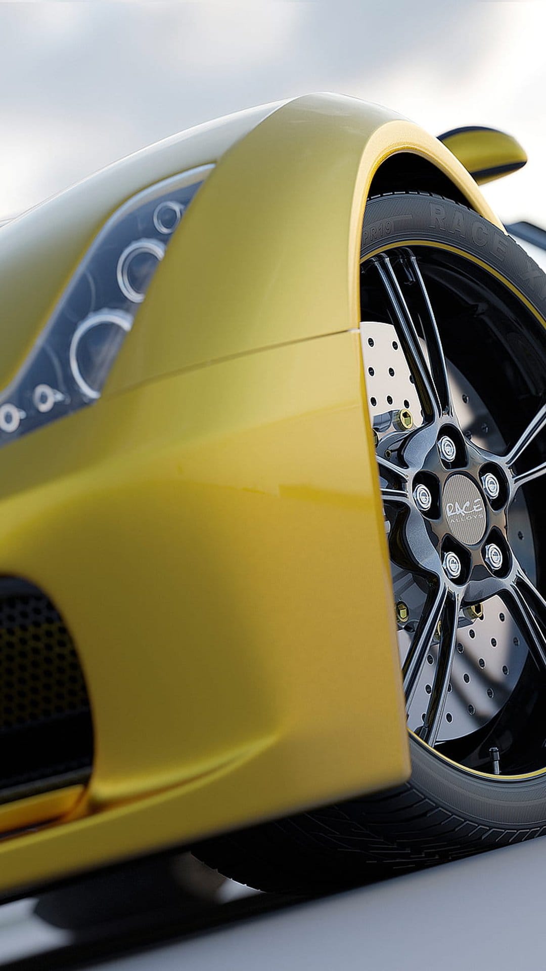 Yellow sports car wheel with perforated brake discs and a circular headlight against a soft blurred sky background.