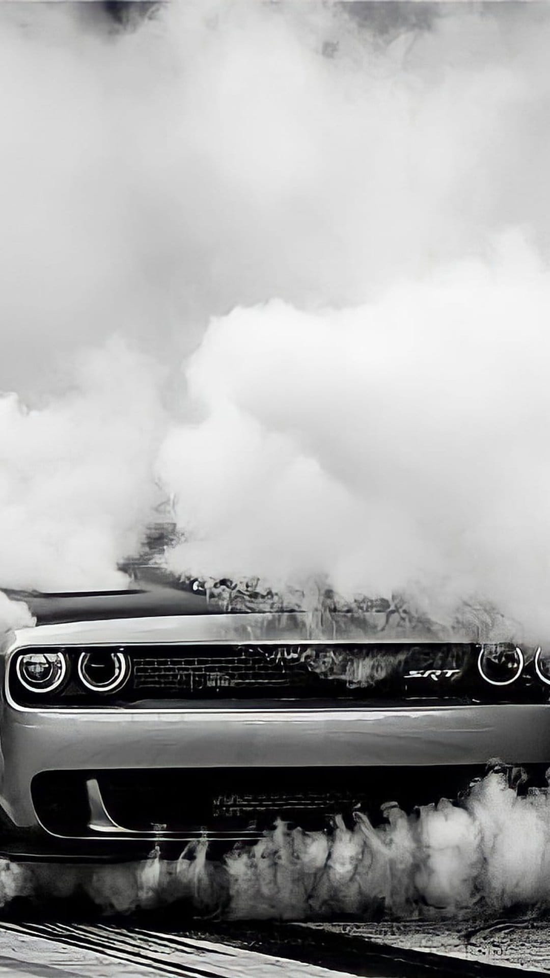 Dodge Challenger SRT Demon muscle car partially obscured by thick smoke plumes in a monochrome action shot.
