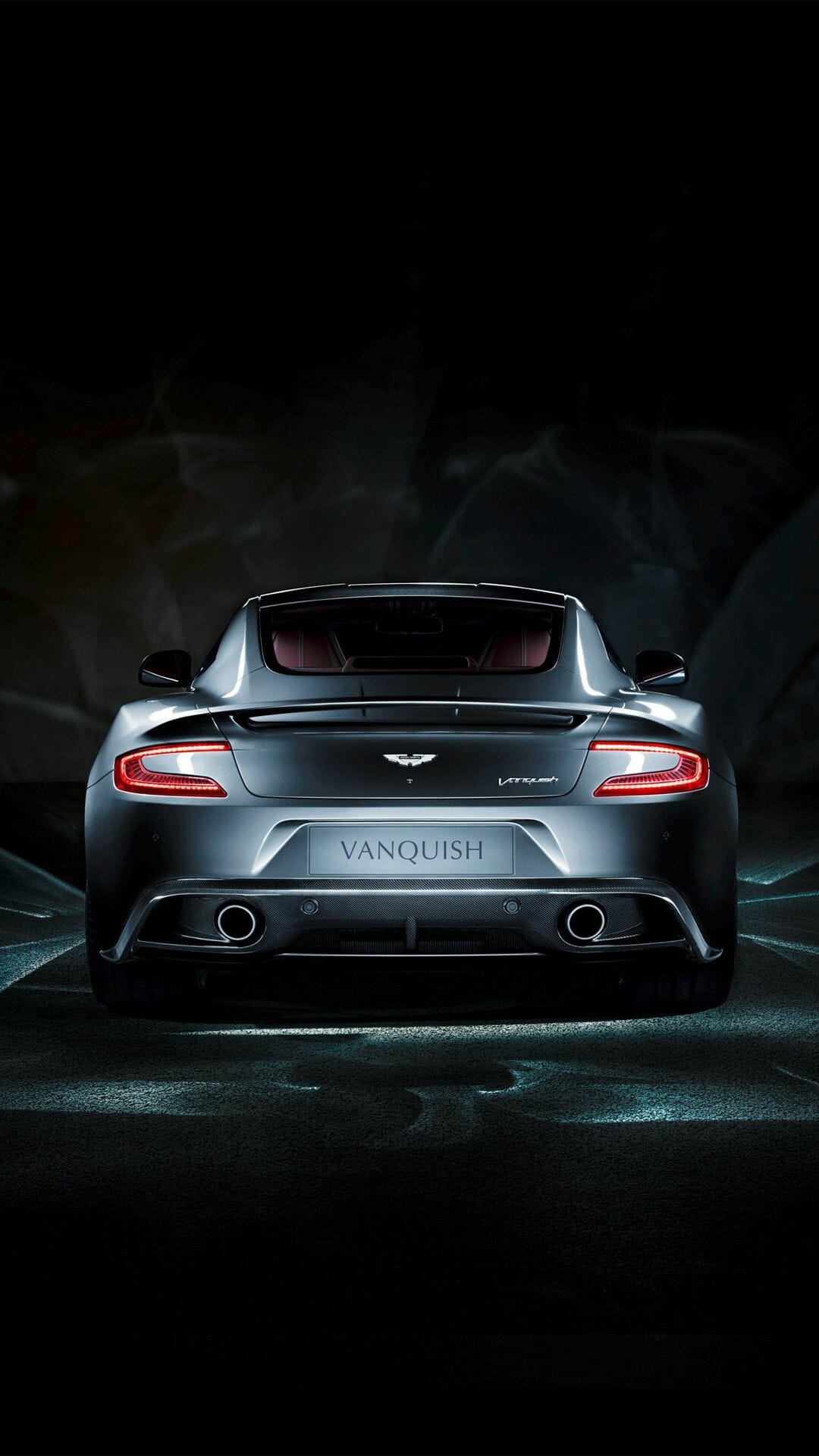 Aston Martin Vanquish rear view featuring glowing red LED taillights against a dark studio background.