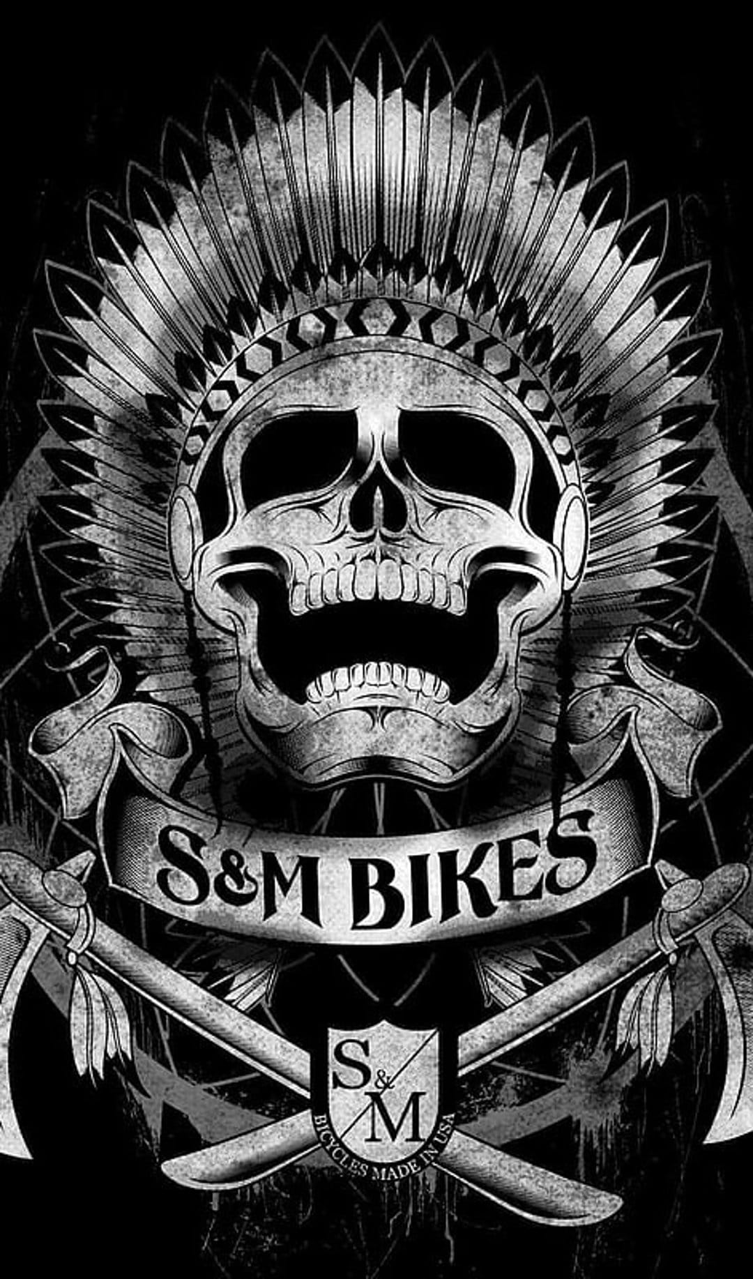 Skull in a feathered headdress with crossed axes and banners displaying S&M Bikes and Bicycles Made in USA text.