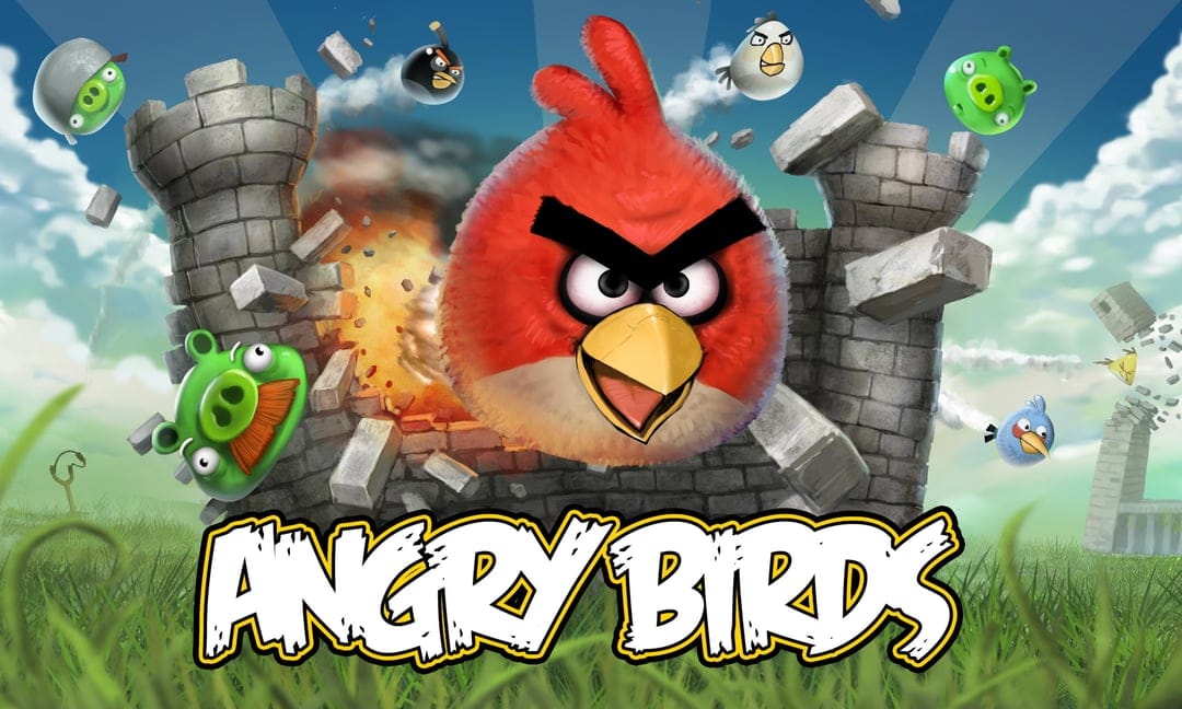 Red Angry Bird crashes through a gray stone castle wall with flying debris, green pigs, and a bright blue sky.
