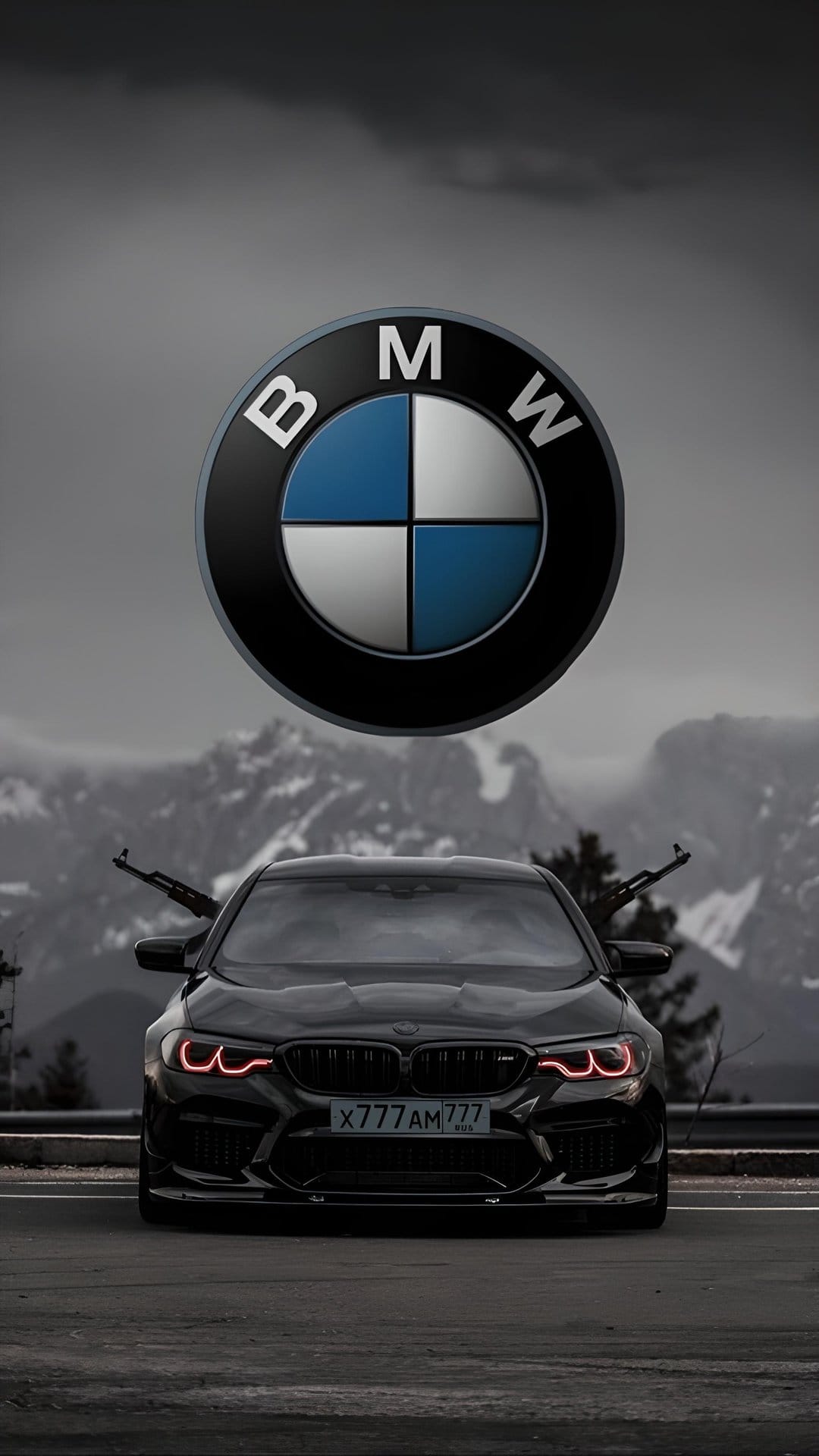 Black BMW M5 with mounted machine guns and red trim parked on a mountain road beneath a dark cloudy sky.