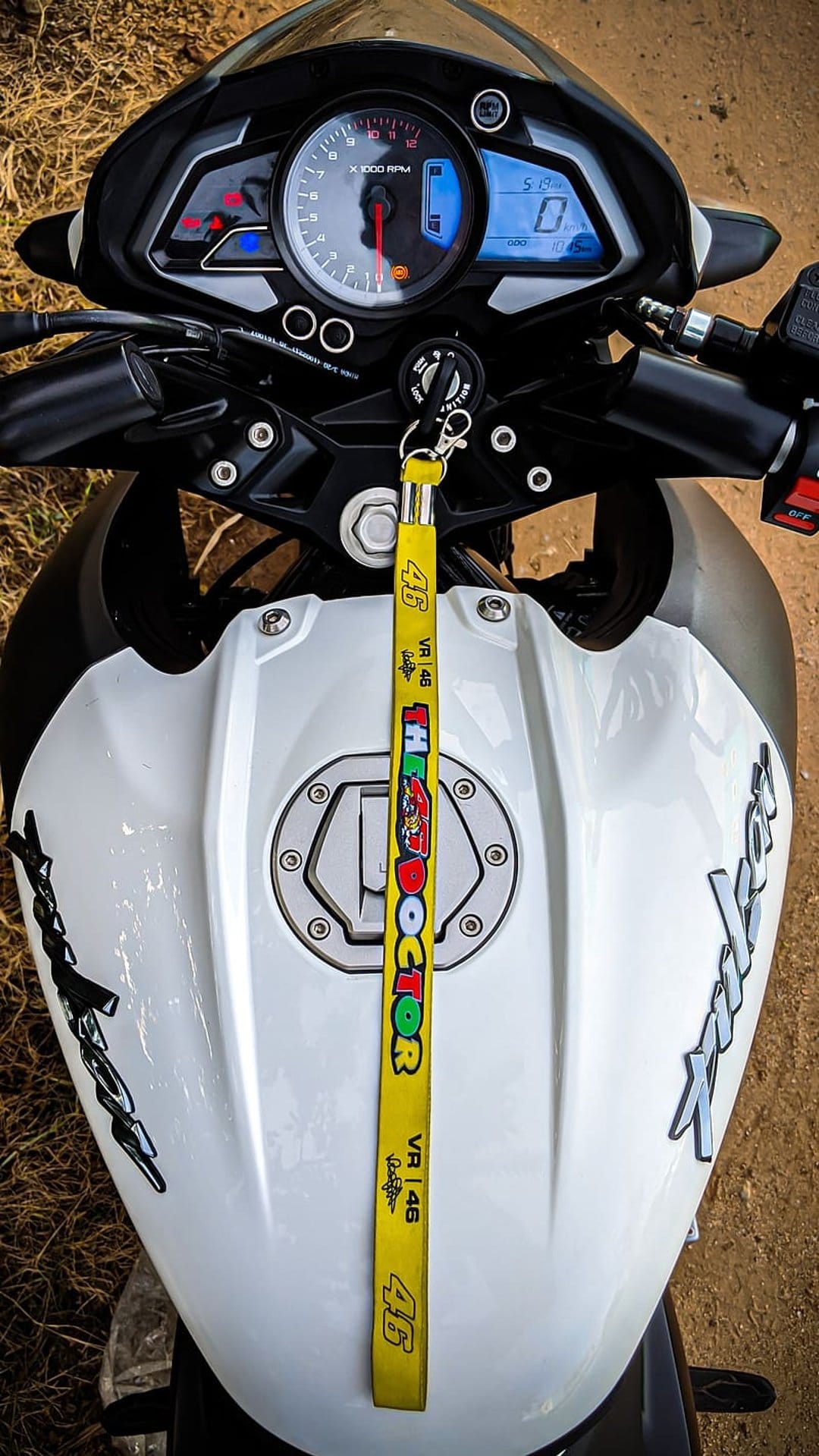 Valentino Rossi VR46 lanyard sits on a motorcycle dashboard featuring a digital display and ignition key.