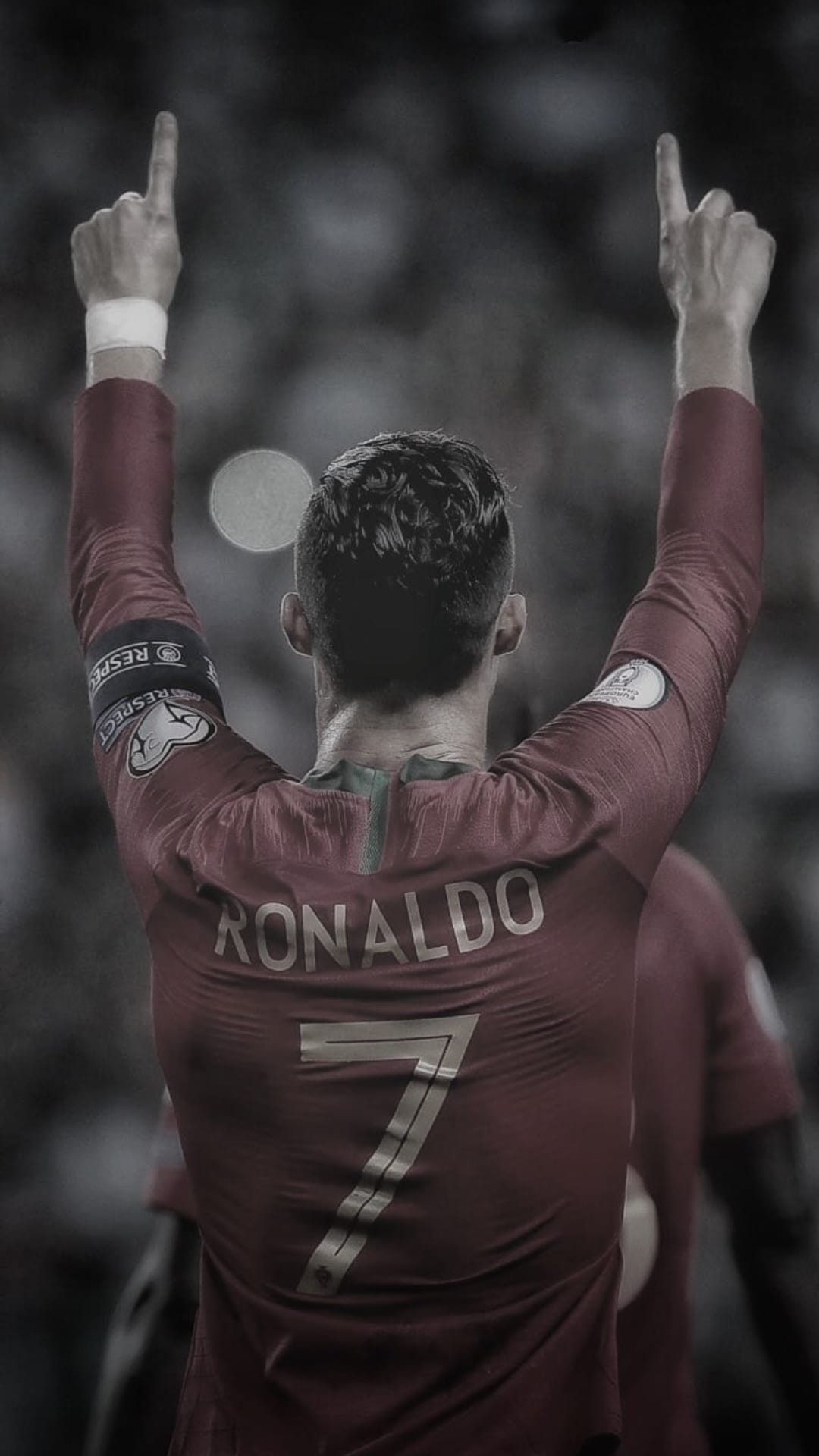 Cristiano Ronaldo viewed from behind wearing a red number 7 jersey with his arms raised in a stadium celebration.