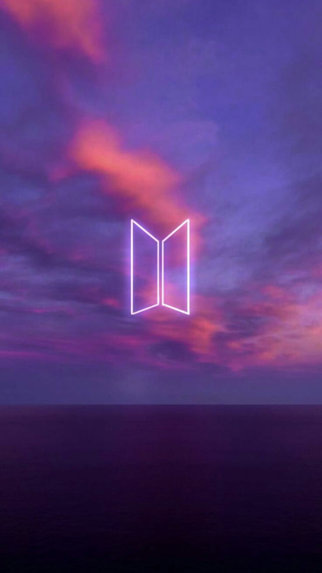 Purple neon BTS logo glows above a twilight horizon with magenta clouds reflecting on a calm water surface.
