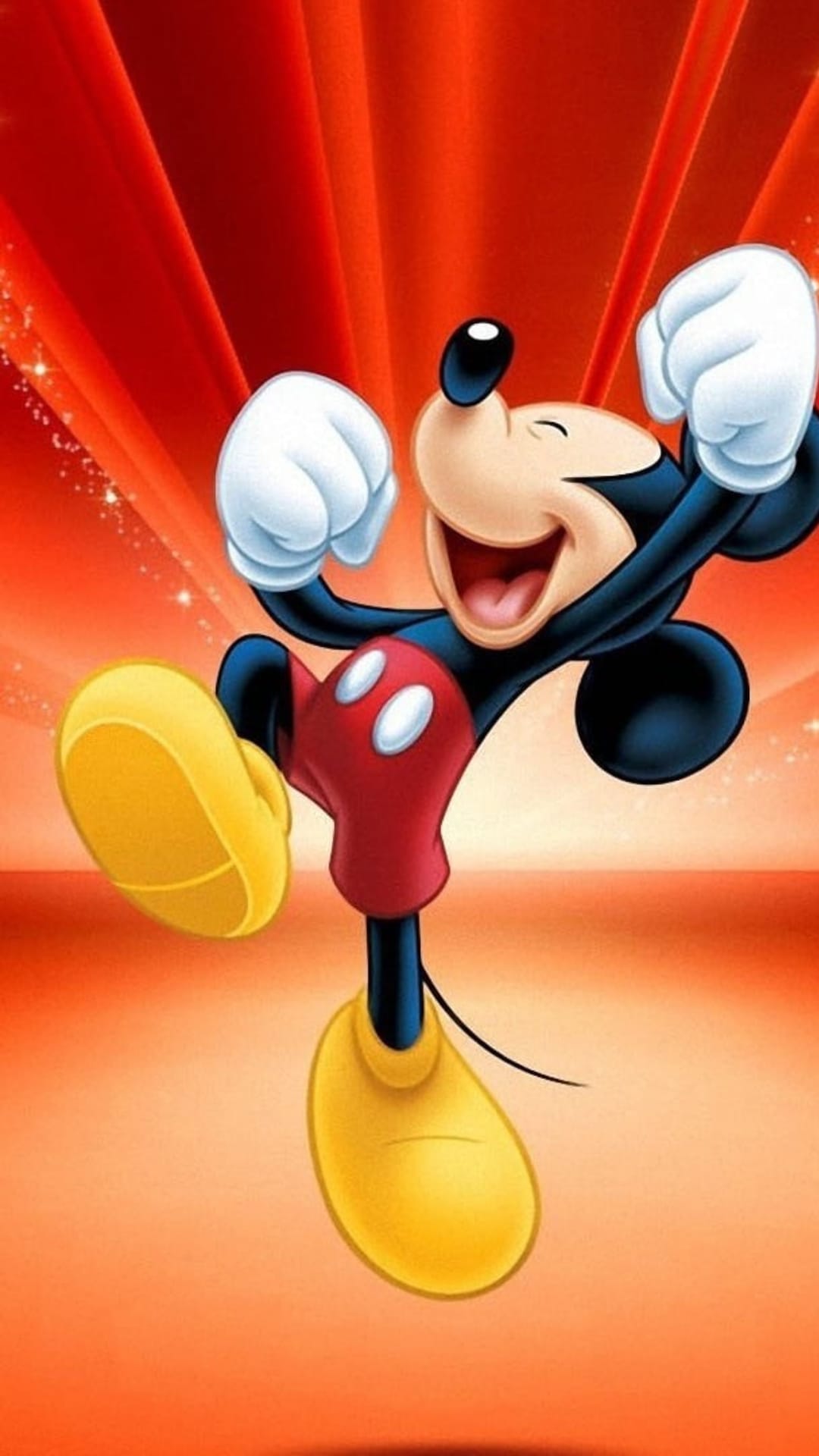 Mickey Mouse jumps with clenched fists and a wide grin amidst red and orange radiating lines and glowing sparkles.