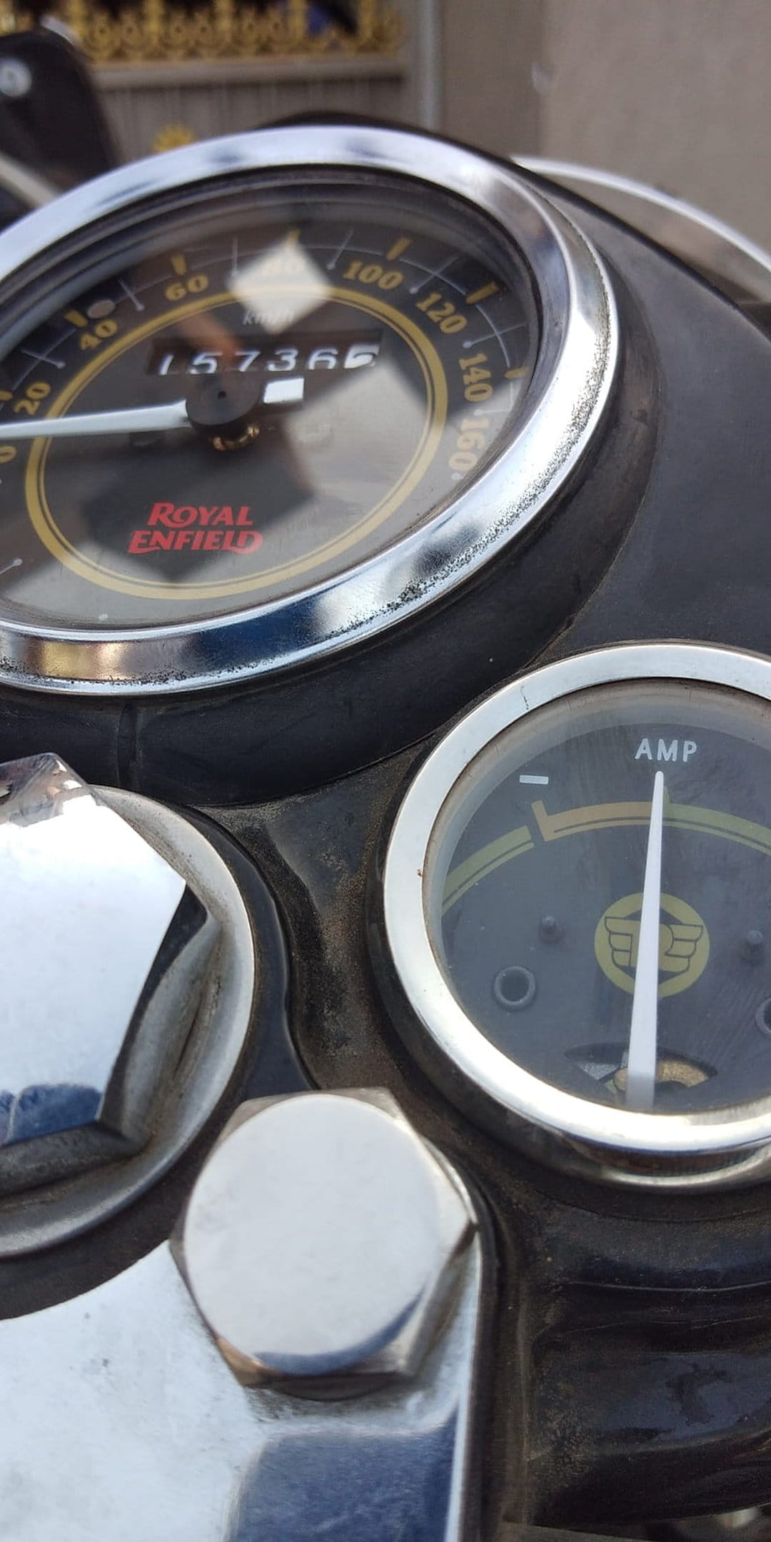 Royal Enfield speedometer and ammeter with chrome bezels and mechanical dials on a vintage motorcycle dashboard.