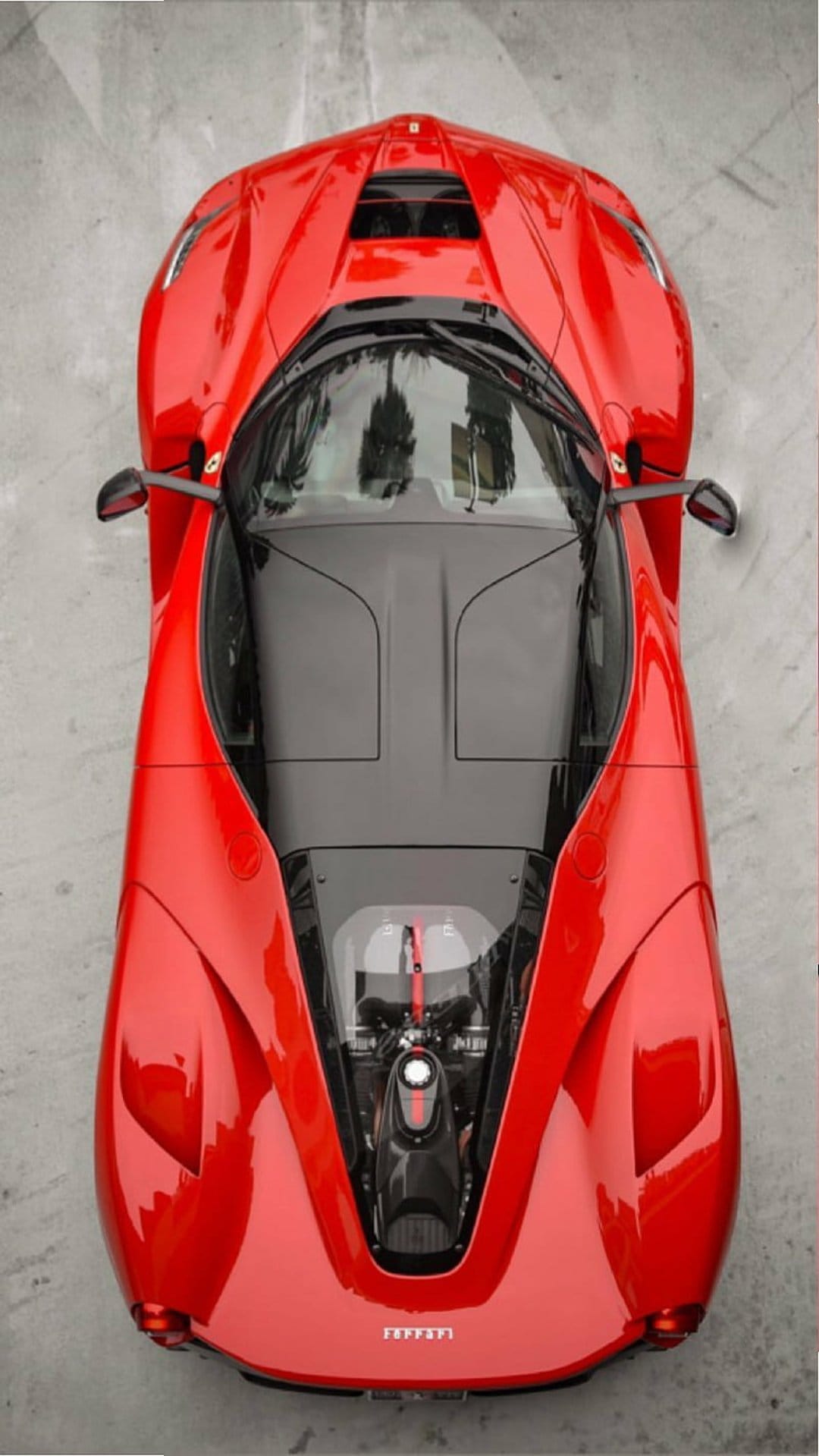 Red Ferrari hypercar viewed from above reveals its exposed engine and aerodynamic carbon fiber body contours.