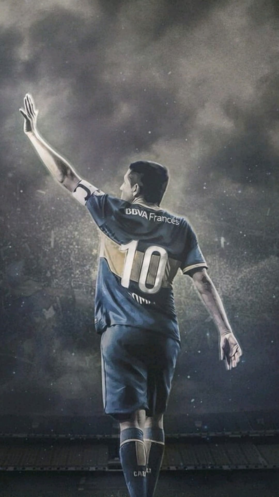 Juan Román Riquelme raises his arm in a blue and gold jersey while standing in a smoky, lit football stadium.