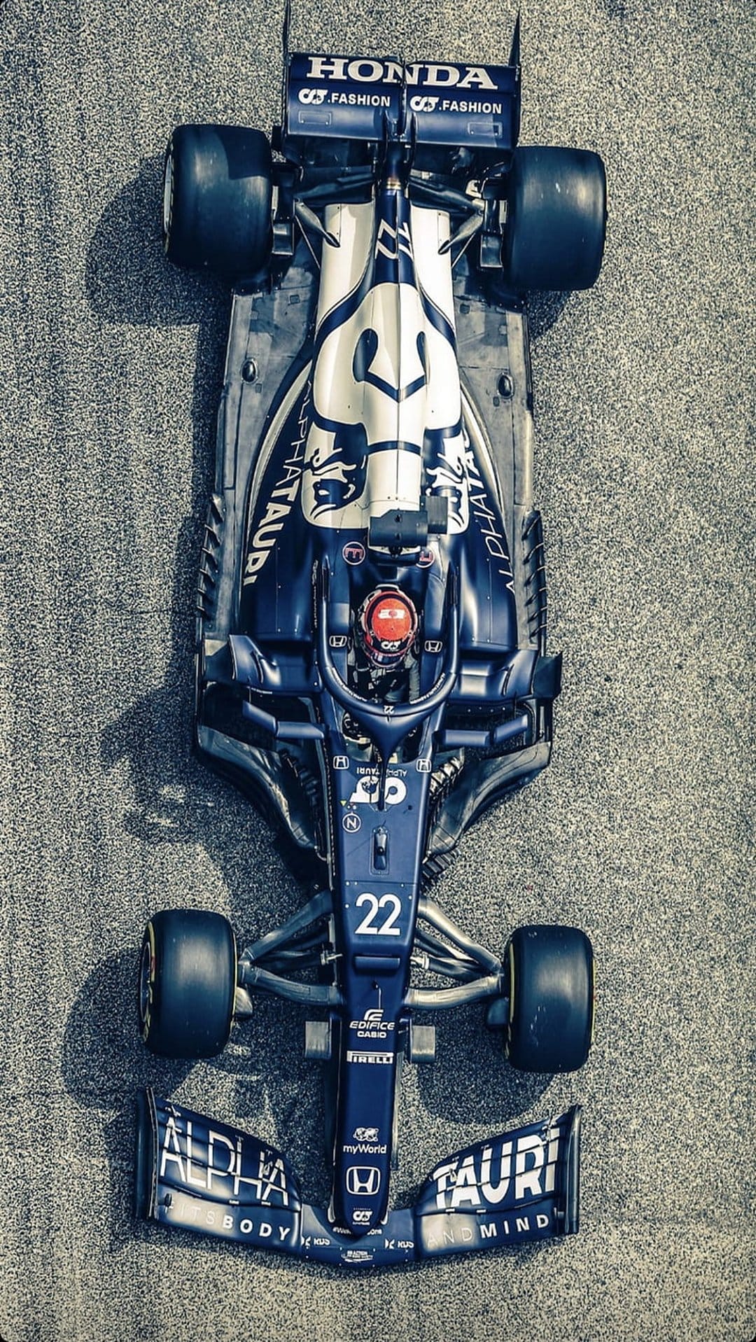 AlphaTauri F1 car number 22 with blue and white livery on a grey asphalt track viewed from directly above.