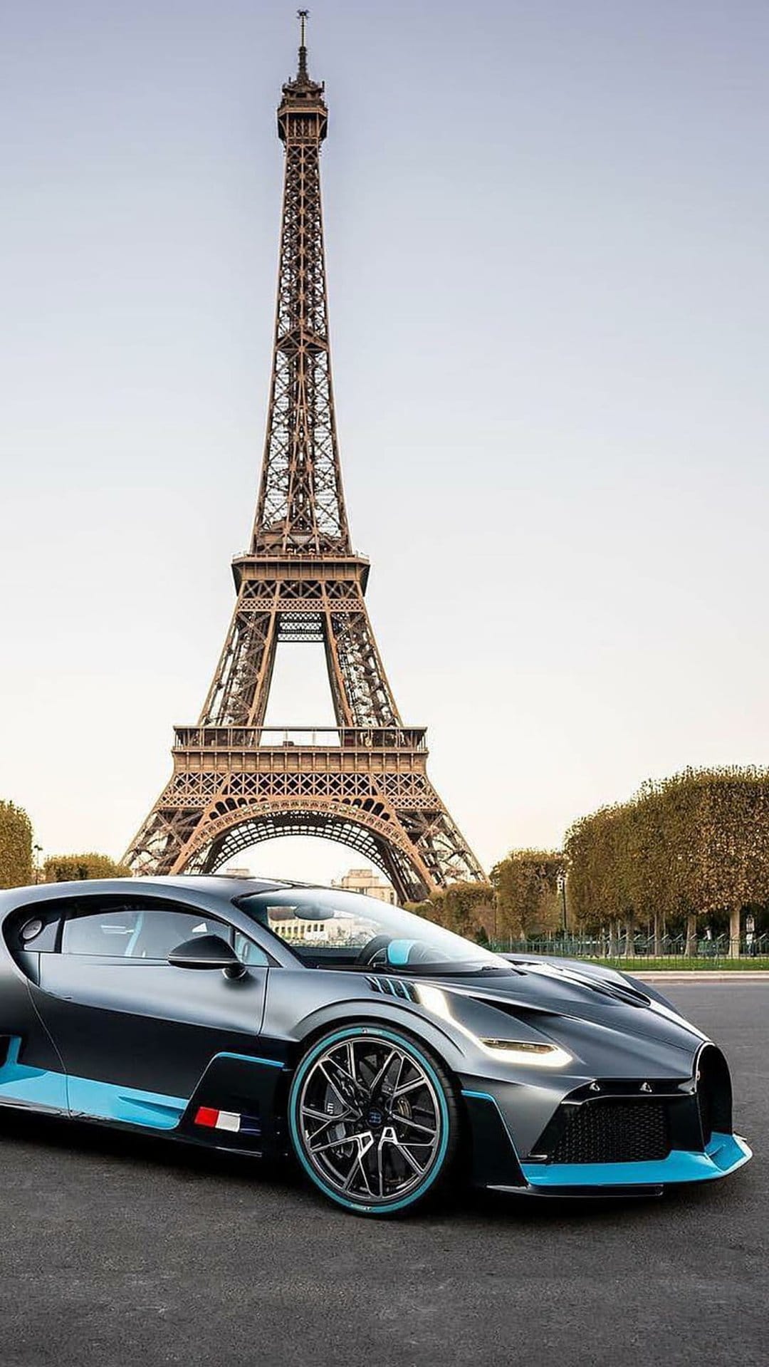 Bugatti Divo supercar parked on a Parisian street with the Eiffel Tower rising into the sky in the background.