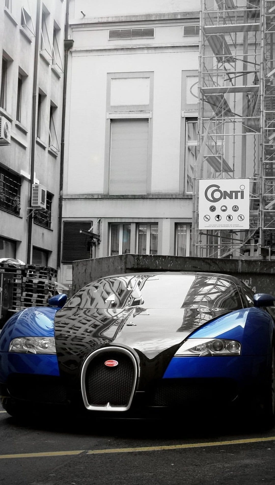 Blue Bugatti Veyron parked in a monochrome alleyway with building reflections on its metallic paint surface.